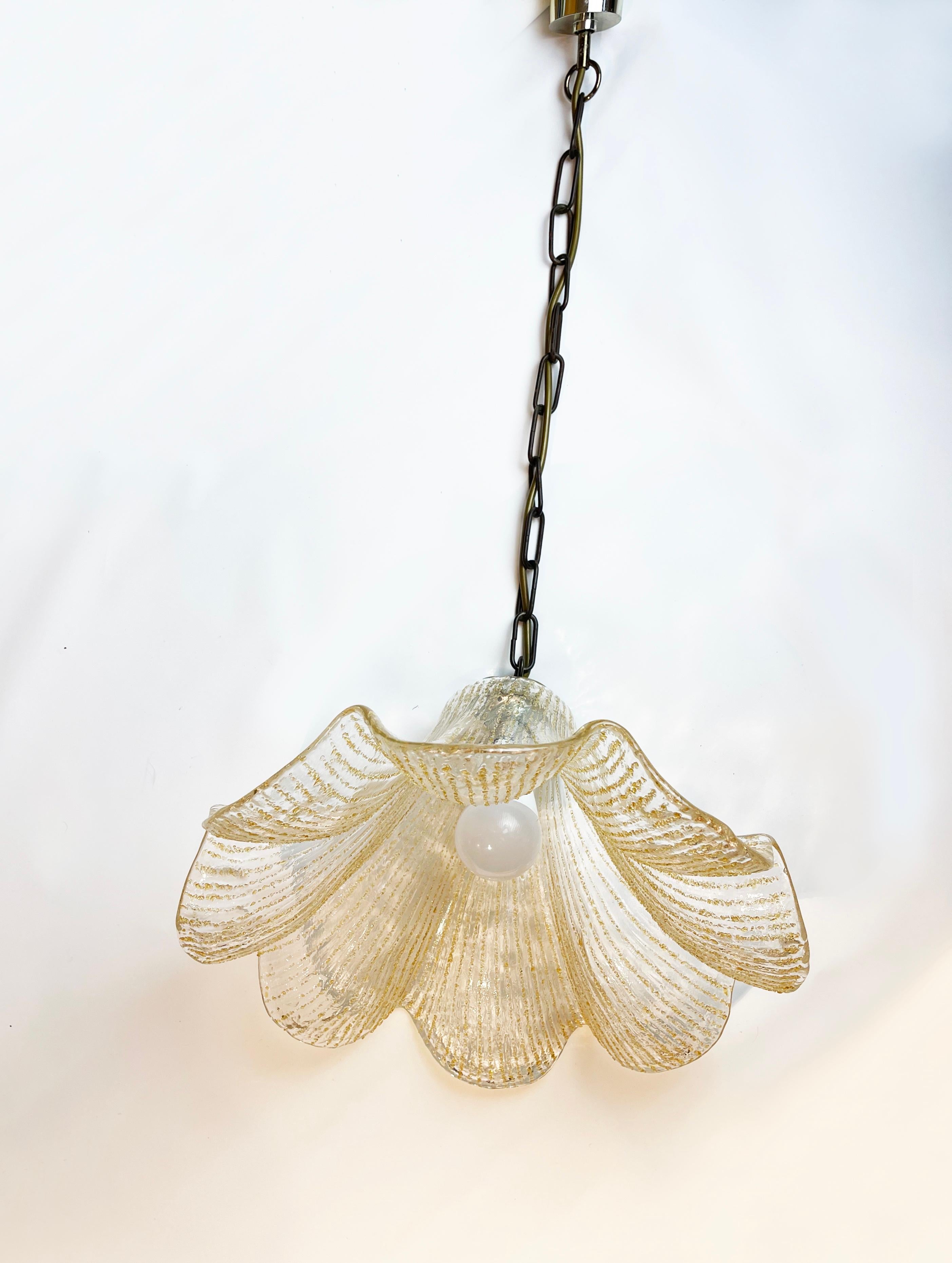 Hand crafted, chunky Murano glass pendant by German mid-century lighting maker Kabo.
A modern German design classic from the late 70s to early 80s in the shape of a gingko-style calyx, in clear glass with golden translucent particles forming stripes
