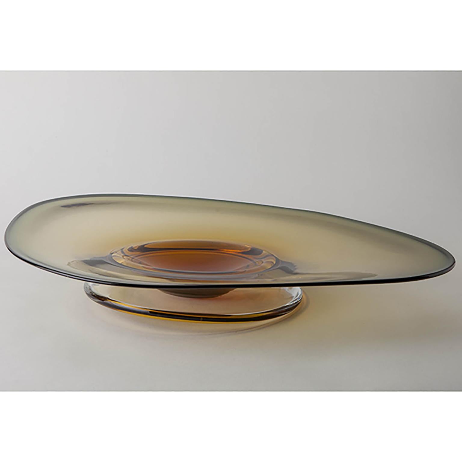 Discover Oculus, a mesmerizing blown glass plate boasting an organic, casual shape. Crafted with meticulous attention to detail, each piece is a testament to the artistry of glassmaking.

The unique form of Oculus is achieved through a fascinating