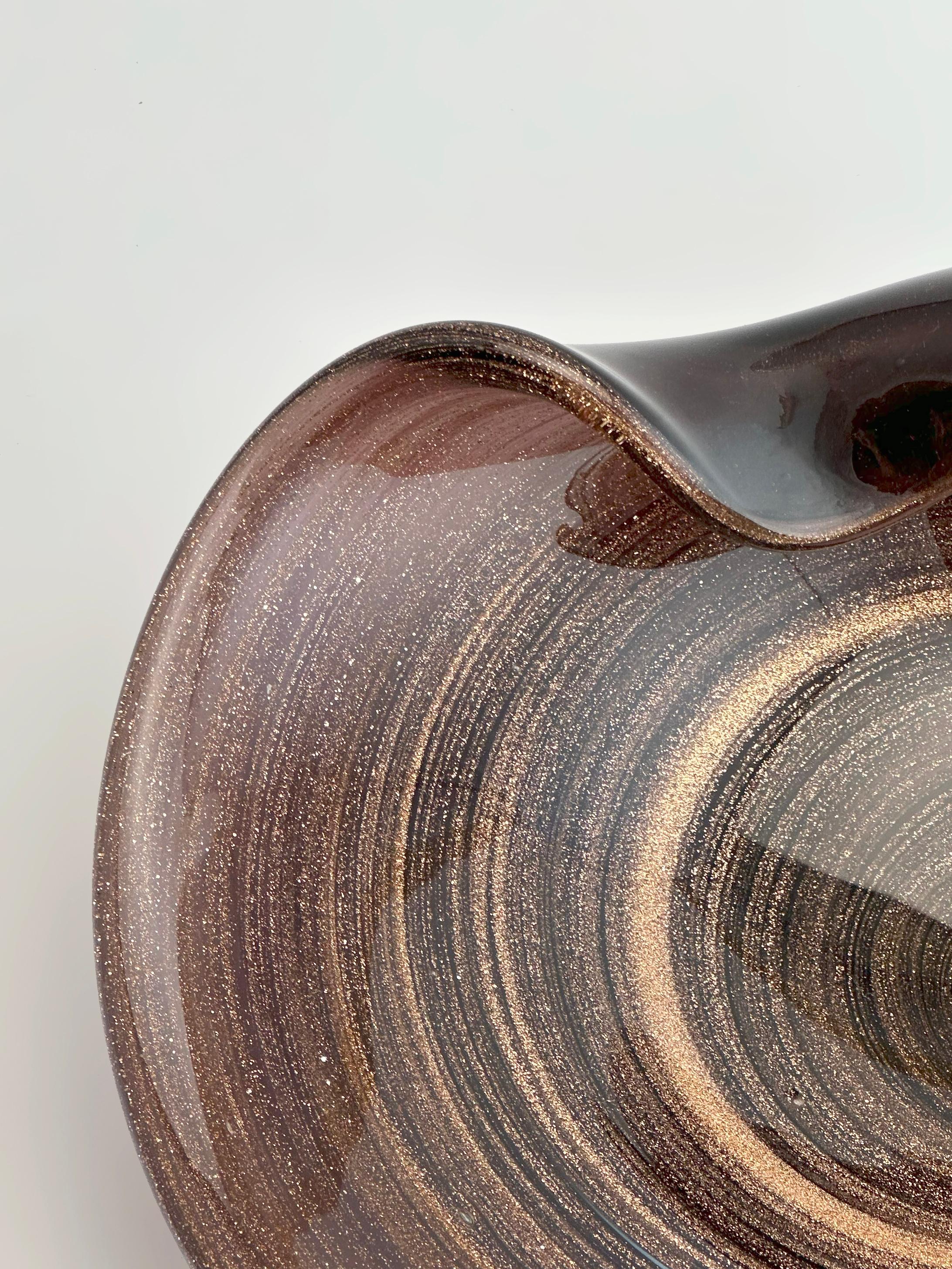 Ciotola da centrotavola in vetro di Murano attribuita a Fratelli Toso, Italia, circa anni '70.

A forma di cerchio con un bordo dolcemente piegato, simile a una conchiglia, questa ciotola di grandi dimensioni è soffiata in vetro viola intenso,