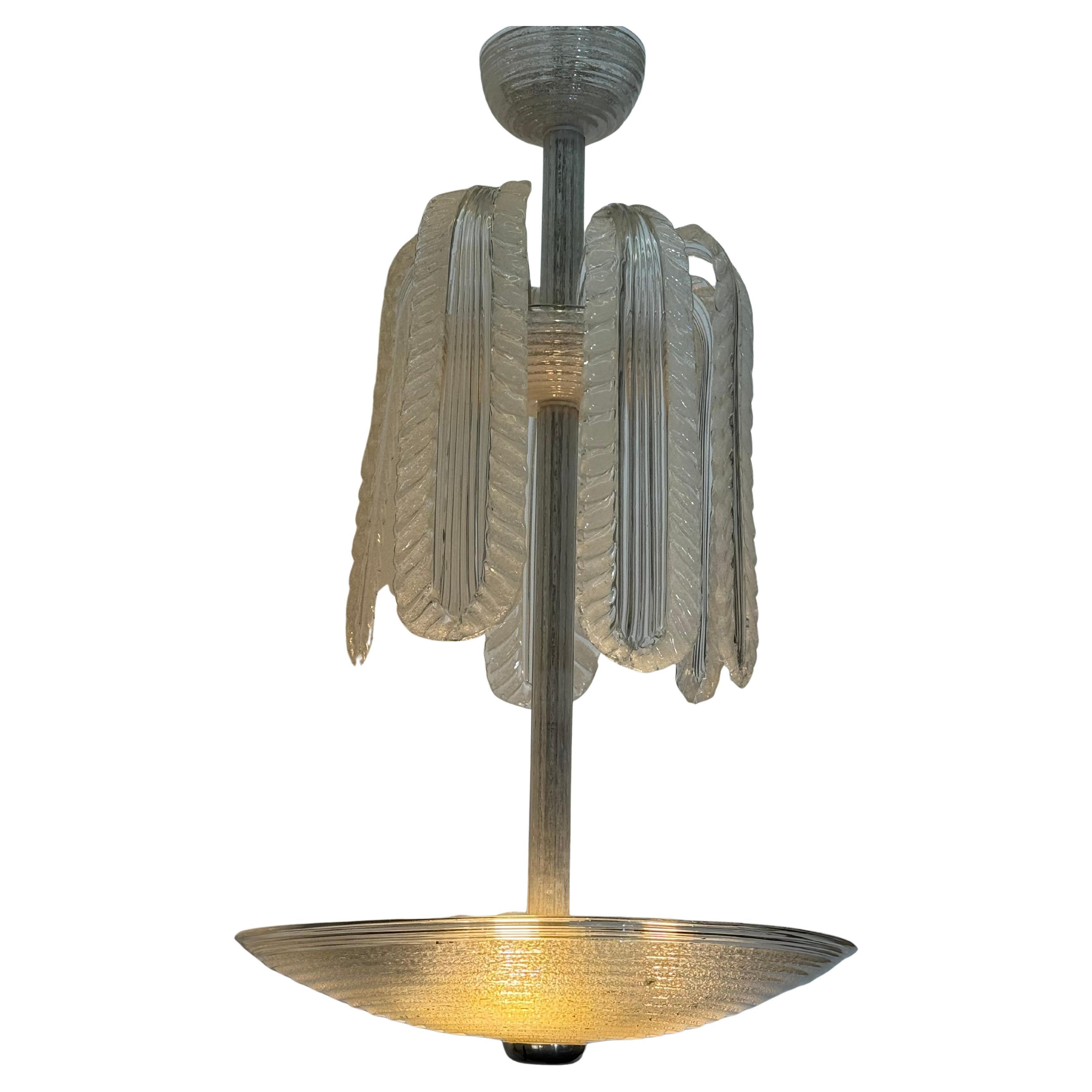 Elegante lampadario in vetro di Murano soffiato a mano, attribuito a Seguso. Il lampadario è caratterizzato da uno stelo centrale in vetro con foglie a cascata a coste che sovrasta un ampio diffusore a ciotola in vetro a coste. La combinazione di