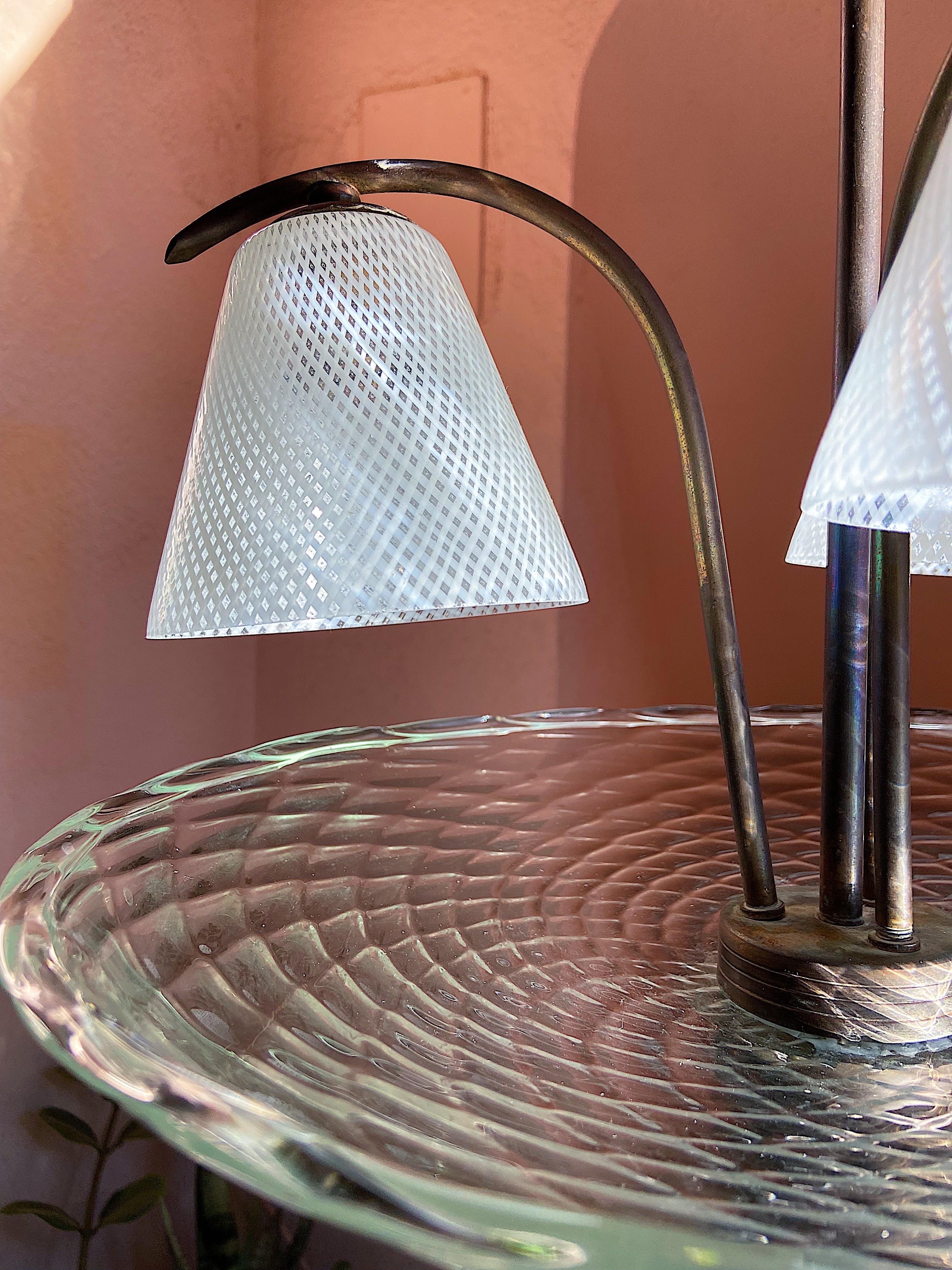 Lustre en verre de Murano, Design/One, Murano, années 1940.
Elle est réalisée en verre d'art de Murano et se compose de 3 cônes en verre posés sur une base en laiton.
Le verre est fabriqué selon la technique dite du Reticello ou Doppia Filigrana,