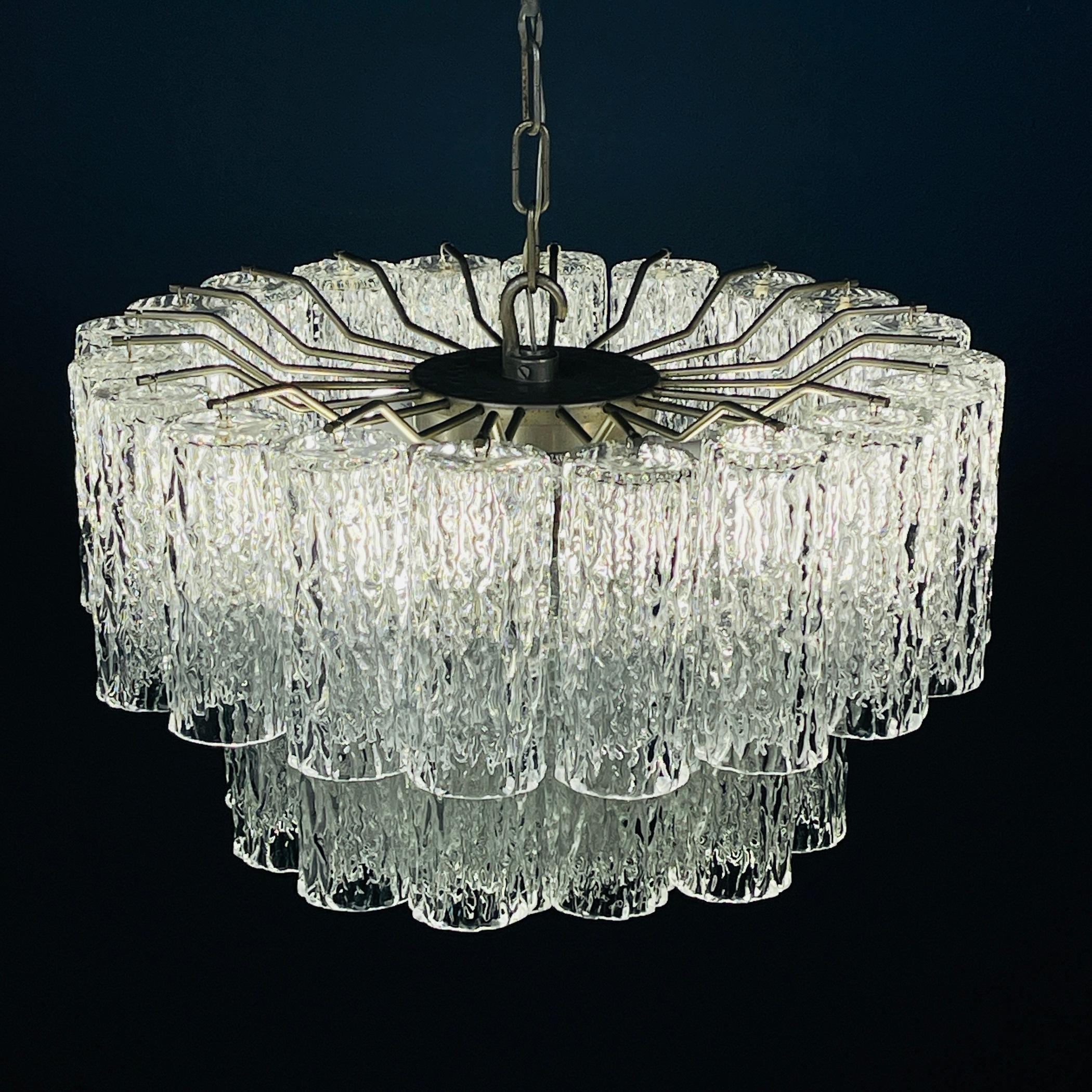 Illuminate your space with the enduring elegance of this Murano glass chandelier, a creation from the 1960s designed by Toni Zuccheri for Venini & Co., a prominent player in the revival of Italy’s high-end glass industry. Venini & Co. brought
