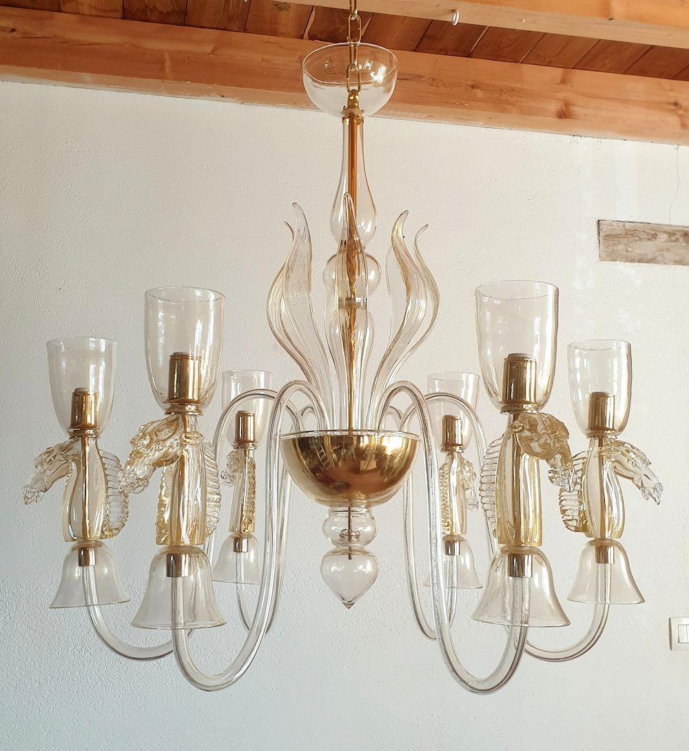 Lustre moderne de Murano du milieu du siècle, Attribué à Archimede Seguso, Italie années 1960.
Le lustre fait main de Murano est en verre clair, avec des inclusions d'or, révélées par la lumière.
Le décor équestre le rend unique.
Un grand lustre,