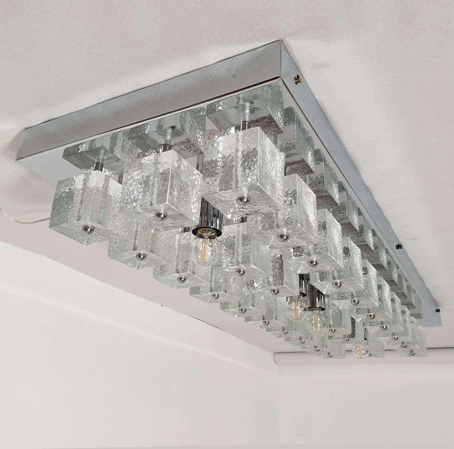 Araña empotrada de cubos de cristal de Murano liso, cromo y transparente, Mid Century Modern.
Atribuido a Gaetano Sciolari, Italia, década de 1980.
Araña italiana de empotrar, de forma geométrica y rectangular.
El empotrable cromado tiene 4 luces,