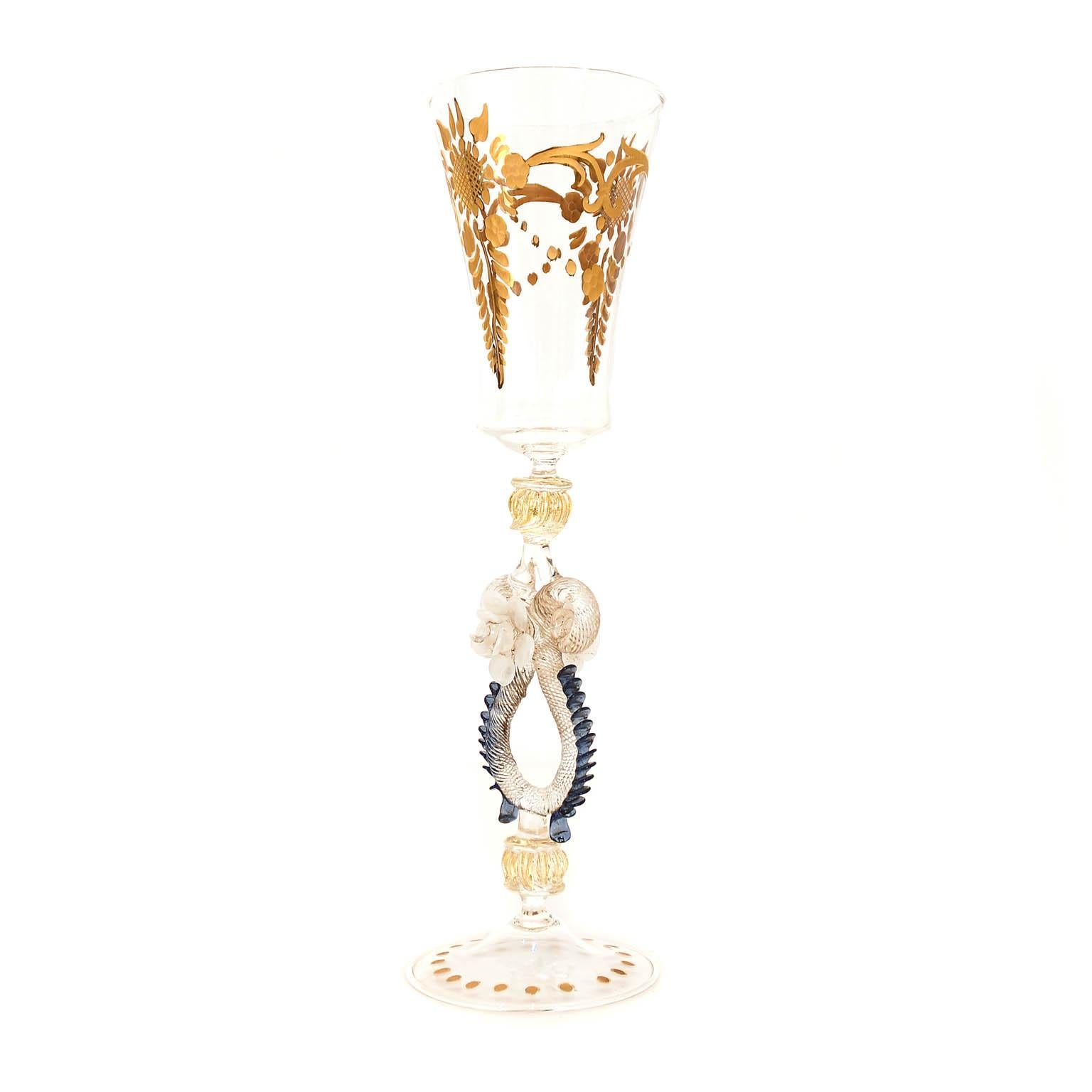 Italian handcrafted chalice in clear, gold, white and blue glass. The stem is cutted and decorated with gold. Due to the cut the gold is glossy and matte.
The base is also decoratied in the same way with dots. The stem is adorned with different