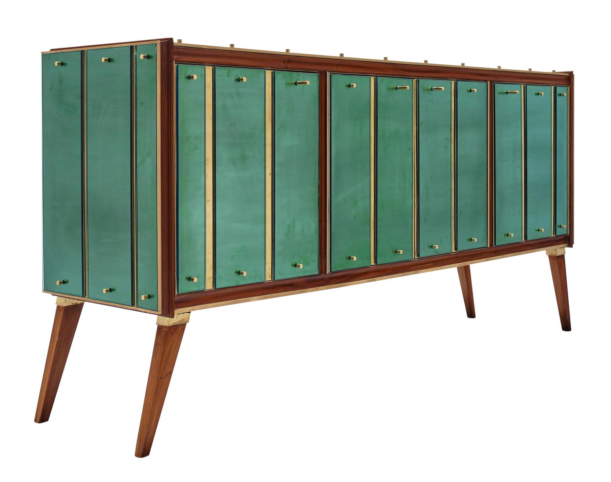 Buffet / enfilade from the Veneto region of Italy. This piece is made of walnut with four doors and flaring tapered legs. The credenza features a brass veneer covered with green slabs of glass maintained to the structure with solid brass spindles.