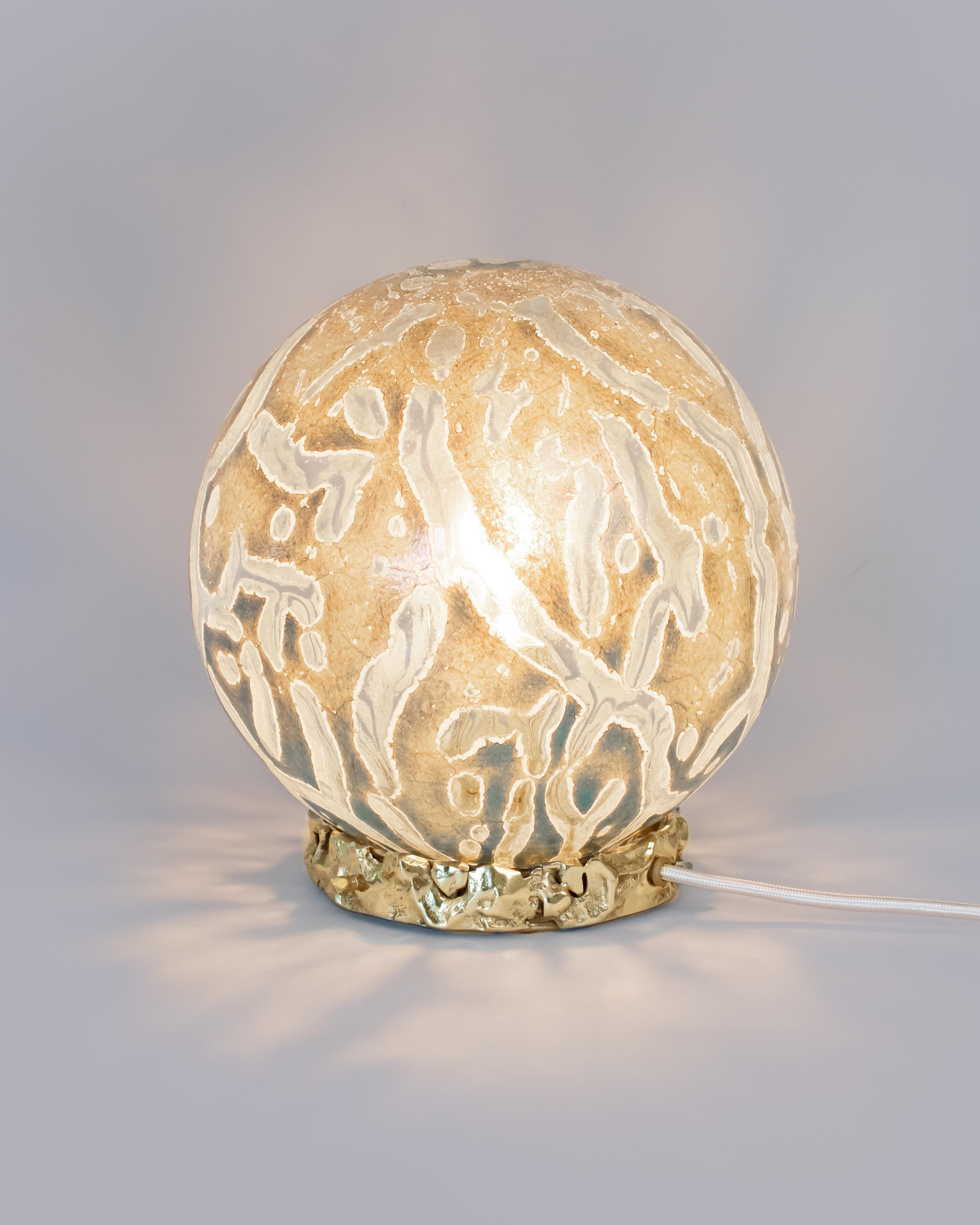 Introducing the Crown Lamp – a luminous piece perfect for enhancing your living room, bedroom or any space you wish to imbue with a touch of luxury and elegance. Its base is crafted from cast brass, featuring an irregular and organically textured