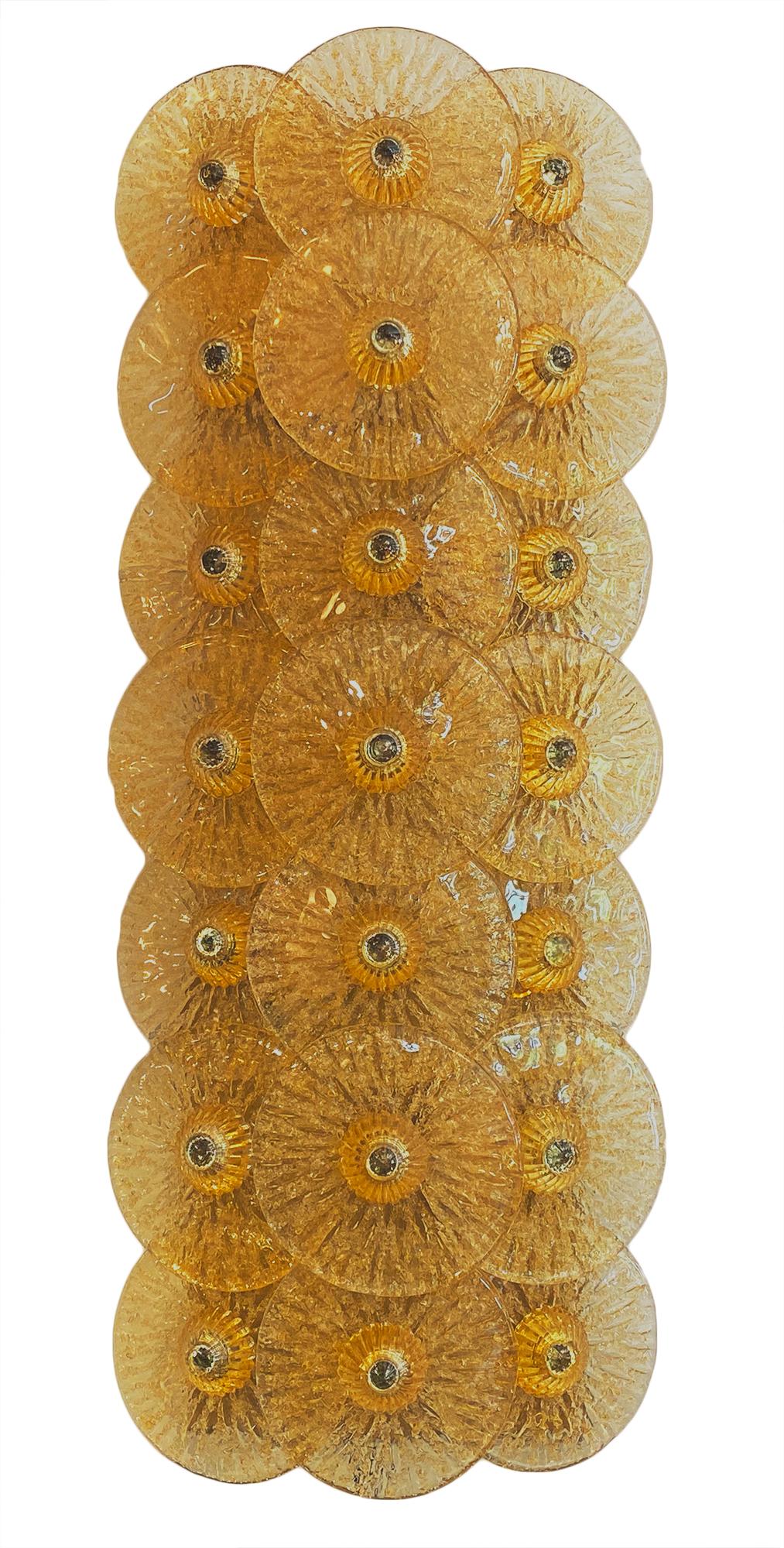 Beautiful Murano glass disc sconces by Carlo Nason. This Italian pair of important fixtures feature 21 light amber hand blown glass discs, each textured and arranged vertically on a polished brass structure. They have been newly wired to fit US