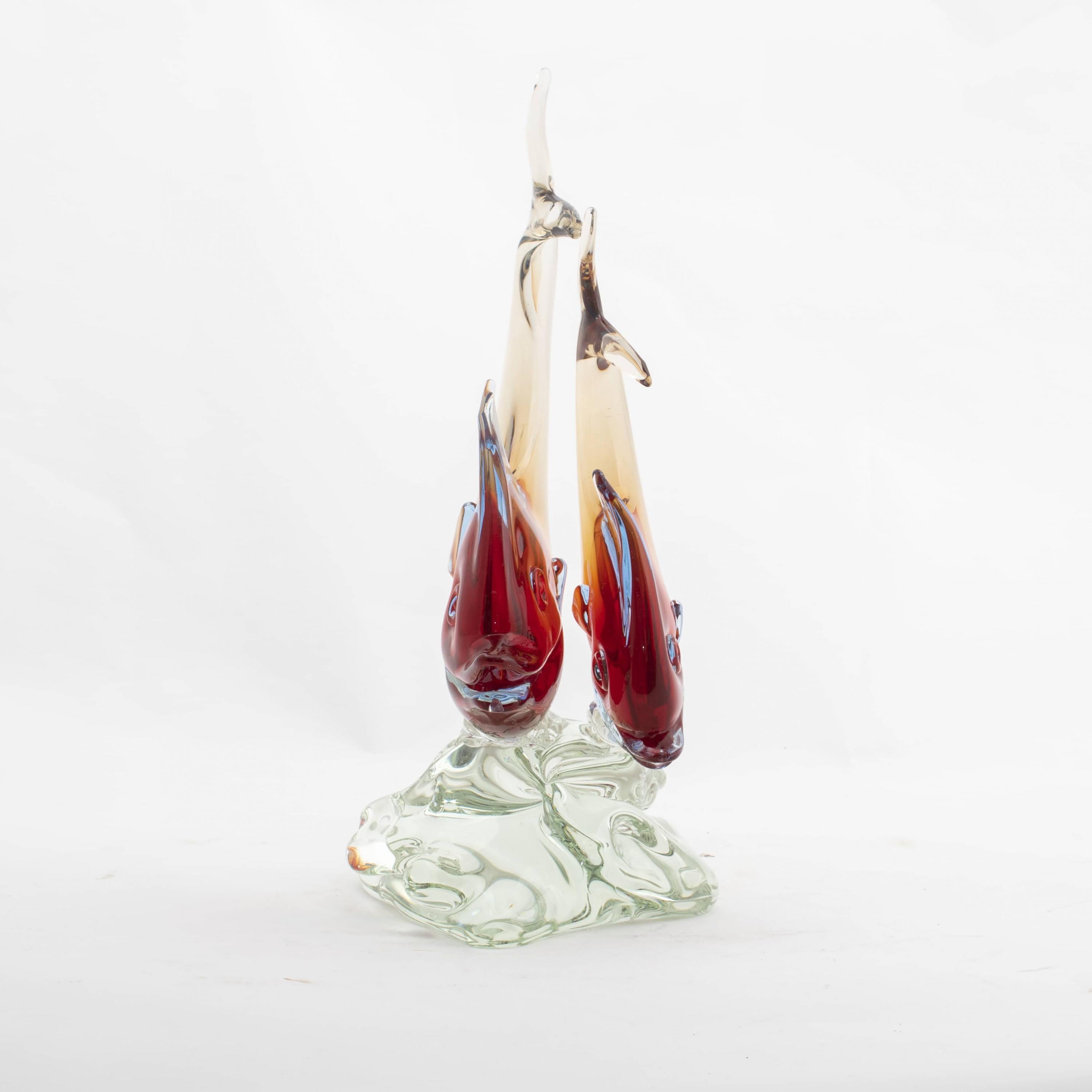 Large and elegant Murano glass art sculpture representing two fish perched on molded base.
This beautiful hand blown glass sculpture is made of translucent glass infused with color. Handcrafted by master Licio Zanetti, at the prestigious glassworks