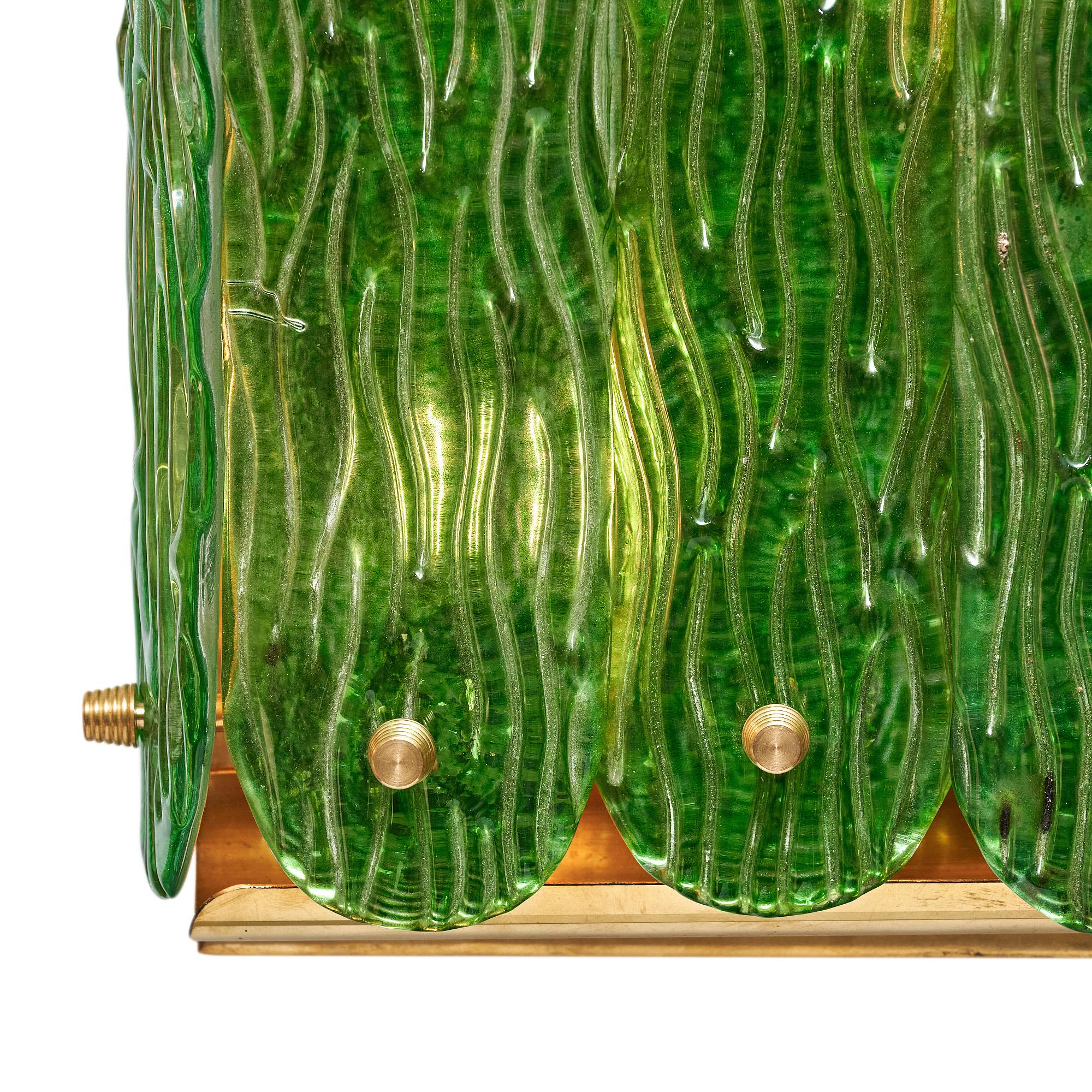 Pareja de apliques de Murano, Italia, a las afueras de Venecia. Cada aplique muestra hojas de cristal verde esmeralda sopladas y moldeadas a mano. Las hojas se sujetan con remates de latón y se apoyan en una estructura de latón. Cada candelabro