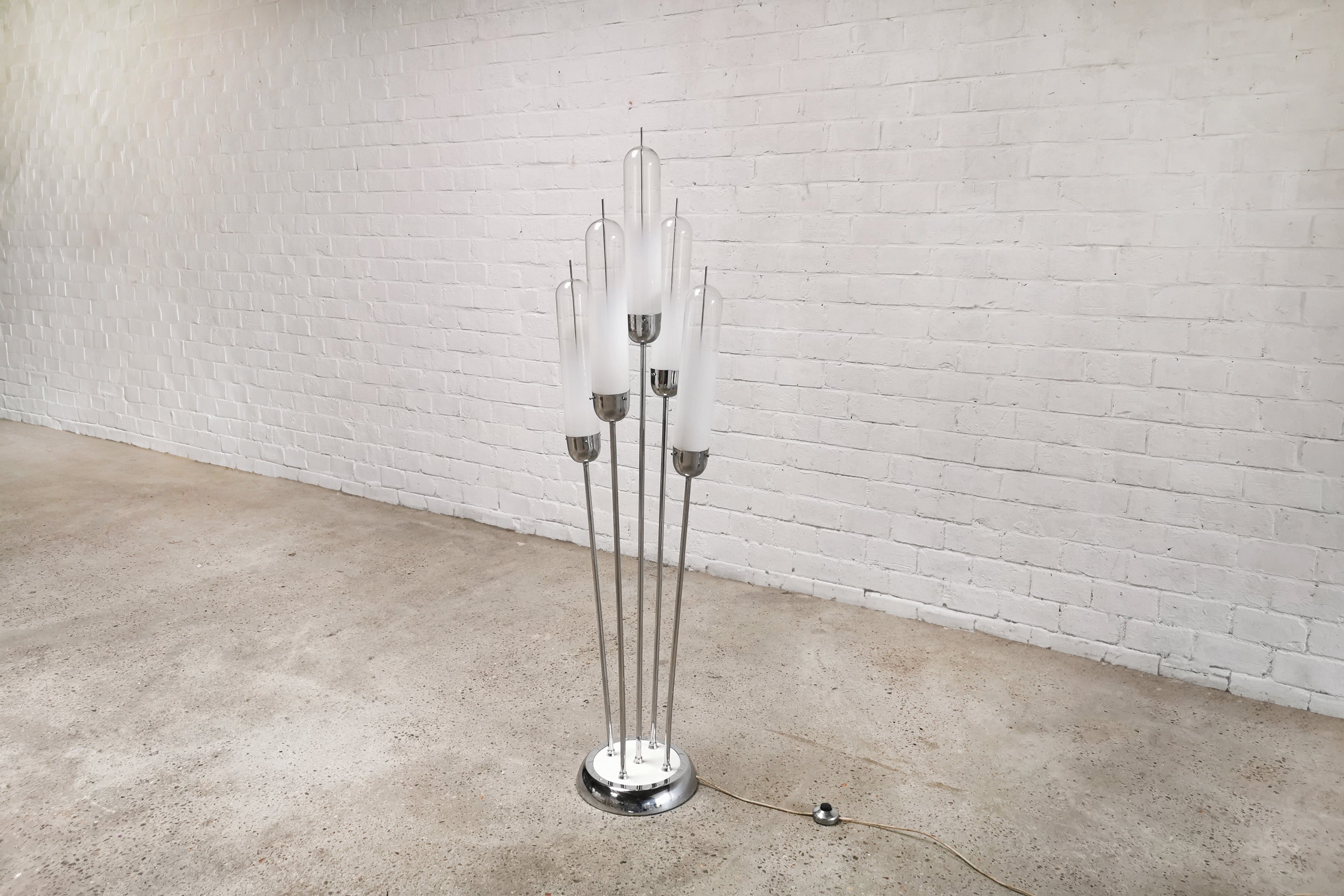 This sculptural five-armed Mid-Century Modern floor lamp was designed by Carlo Nason for Mazzega in the 1970s in Italy. Notably, it is chrome plated and has a base with white accents. Its shades are crafted from mouth-blown Murano glass, showcasing