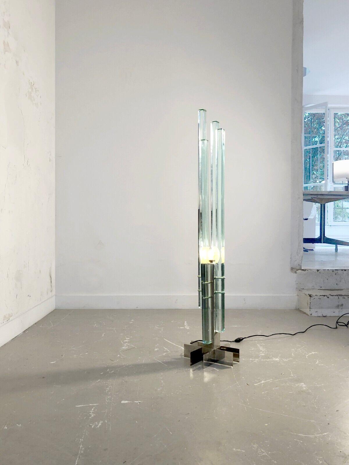 An exceptional floor lamp, Post-Modern, Radical, Constructivist, Sculptural and Kinetic, base in chromed metal strips screwed in cross, holding 4 thick monoliths of translucent blueish Murano Glass, arranged around a square suspended axis, in an