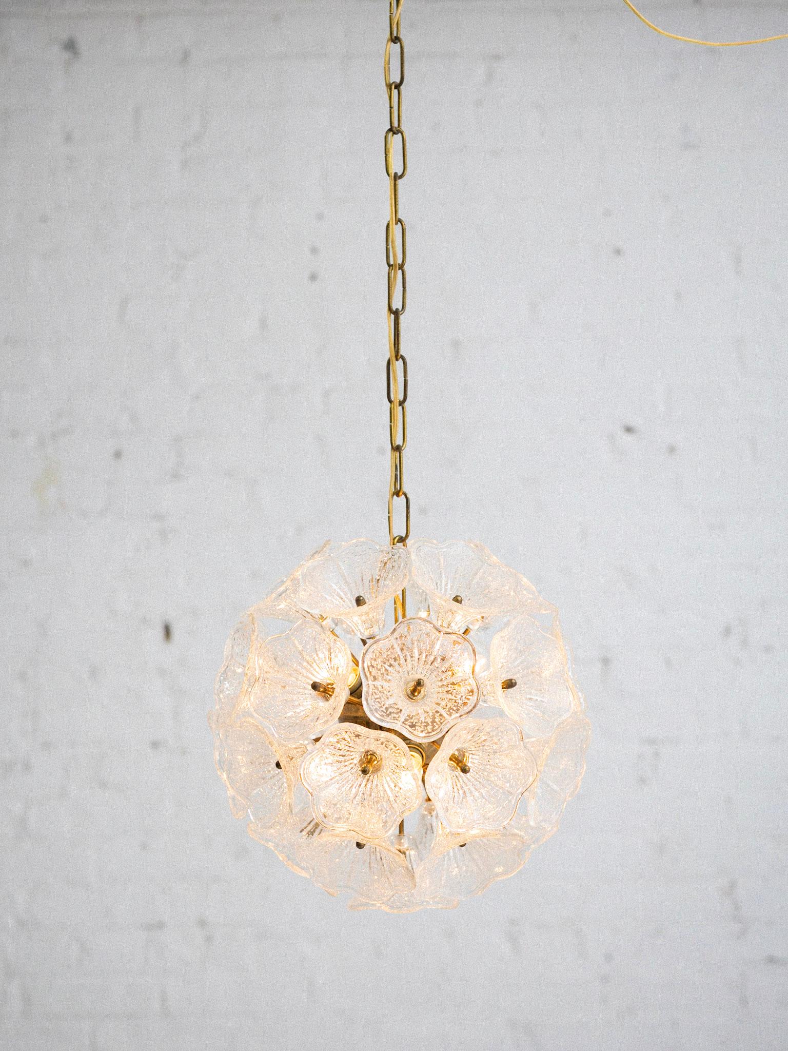 An Italian Murano glass chandelier attributed to Paolo Venini for VeArt. Handblown glass flowers are held by brass hardware radiating from a center brass orb. Wiring recently updated to suit American standards. Current chain measures 28”.