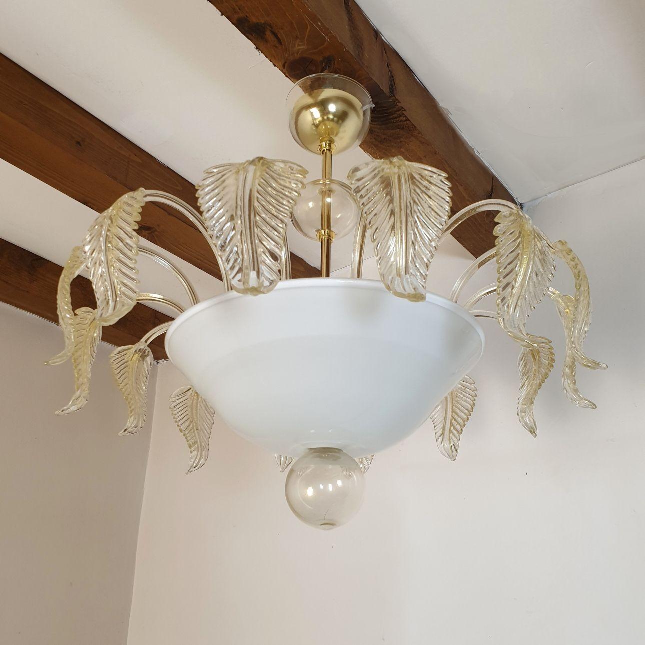 Medium size Mid-Century Modern Murano glass flush mount ceiling light, attributed to Seguso, Italy 1980s.
The chandelier is made of a white translucent bowl, nesting 3 lights, and clear and gold leaves around it.
The mounts are gold plated.
There
