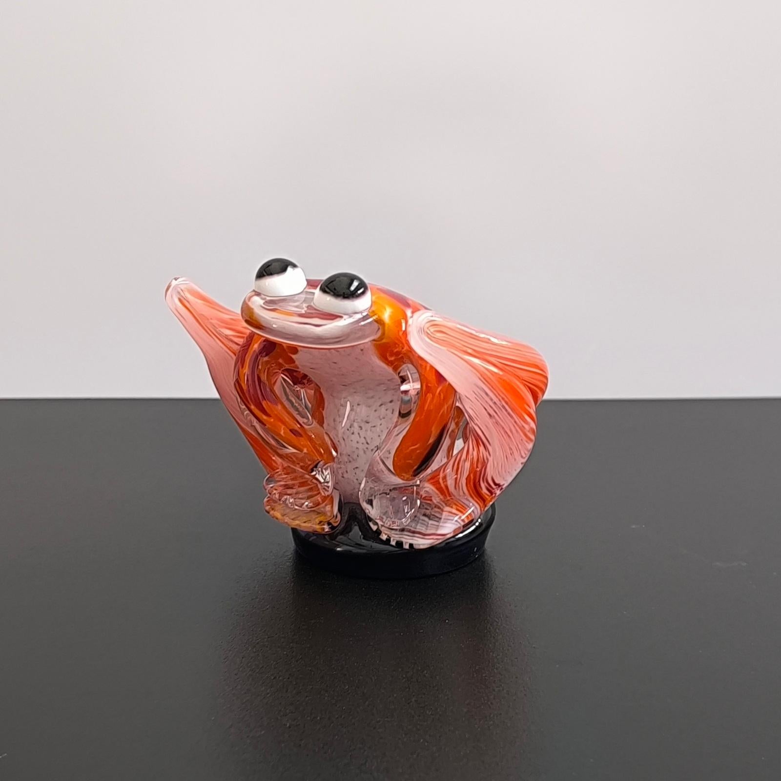 Escultura de rana de cristal de Murano, hacia la década de 1970. La pieza está en muy buen estado vintage, sin astillas ni grietas. El vidrio moteado rojo, naranja, salmón y blanco encerrado en cristal grueso transparente, que descansa sobre una