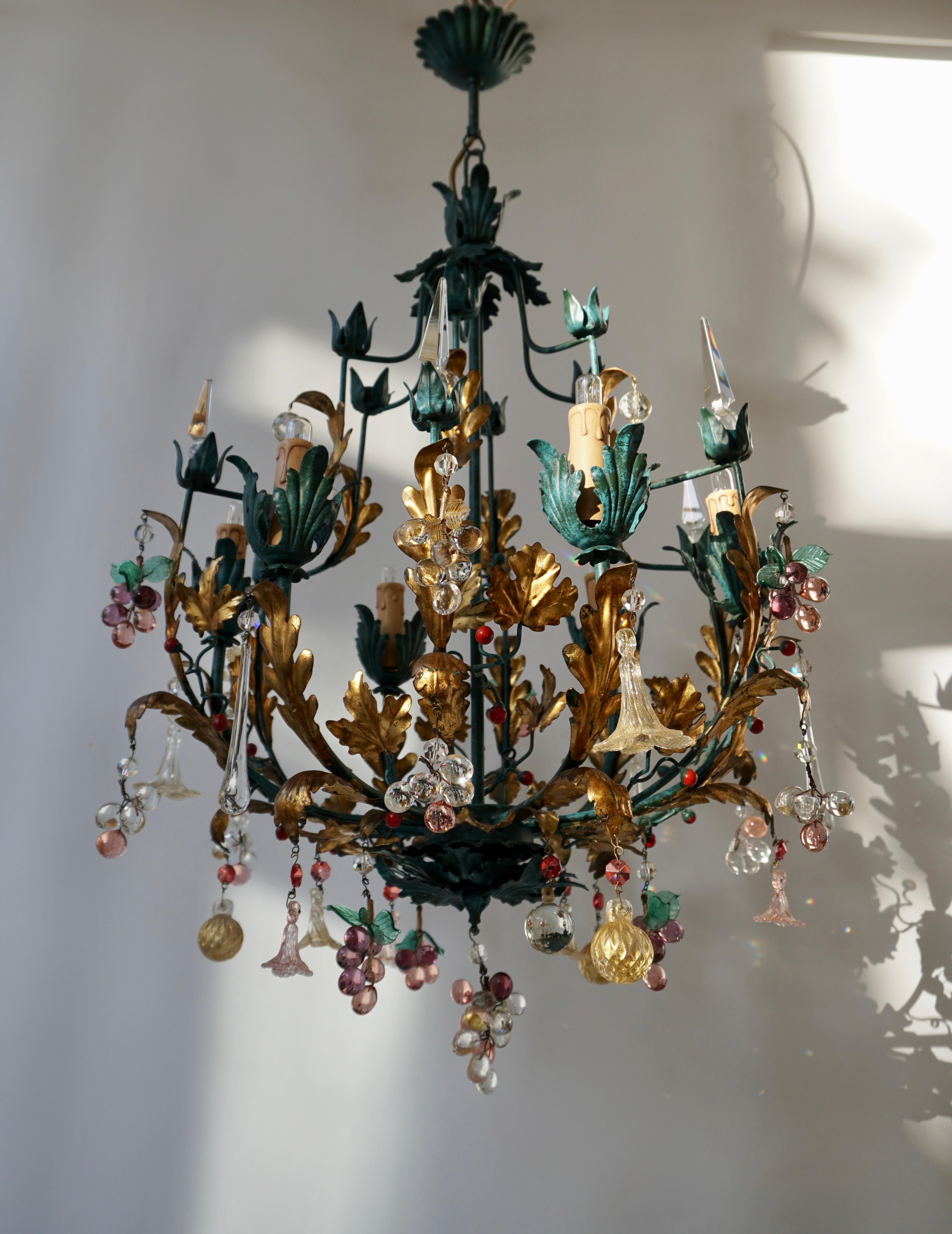 A chandelier from Italy manufactured in midcentury, circa 1950.
It is made of leaf gold-plated metal frame decorated with colorful glass fruits and clear cut glass.
The light is in very good and refurbished condition. This precious item brings