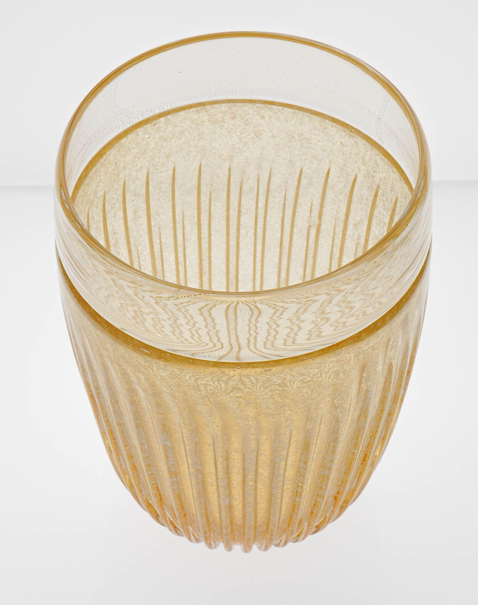 Large beautiful base with the unique tecnique of Incalmo, where the upper band is in clear glass and gold 24K leaf. The body is instead ribbed with deep pulegoso inside amber glass.
Beside the skillful sum of techniques what makes this vase