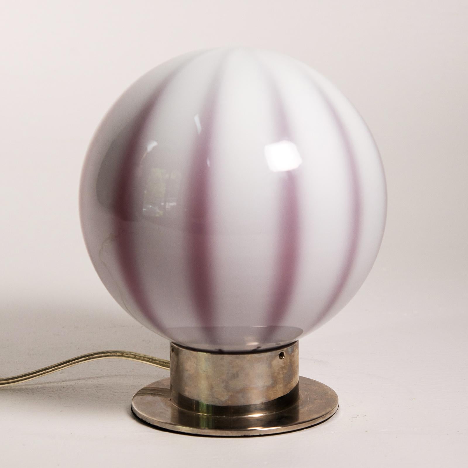Murano glass globe shaped table lamp the cased glass shade with red/purple tones with white panels fitting into a silver plate base. When the lamp is off, it is more purple, when on shines red. Made in Italy by Global Views.