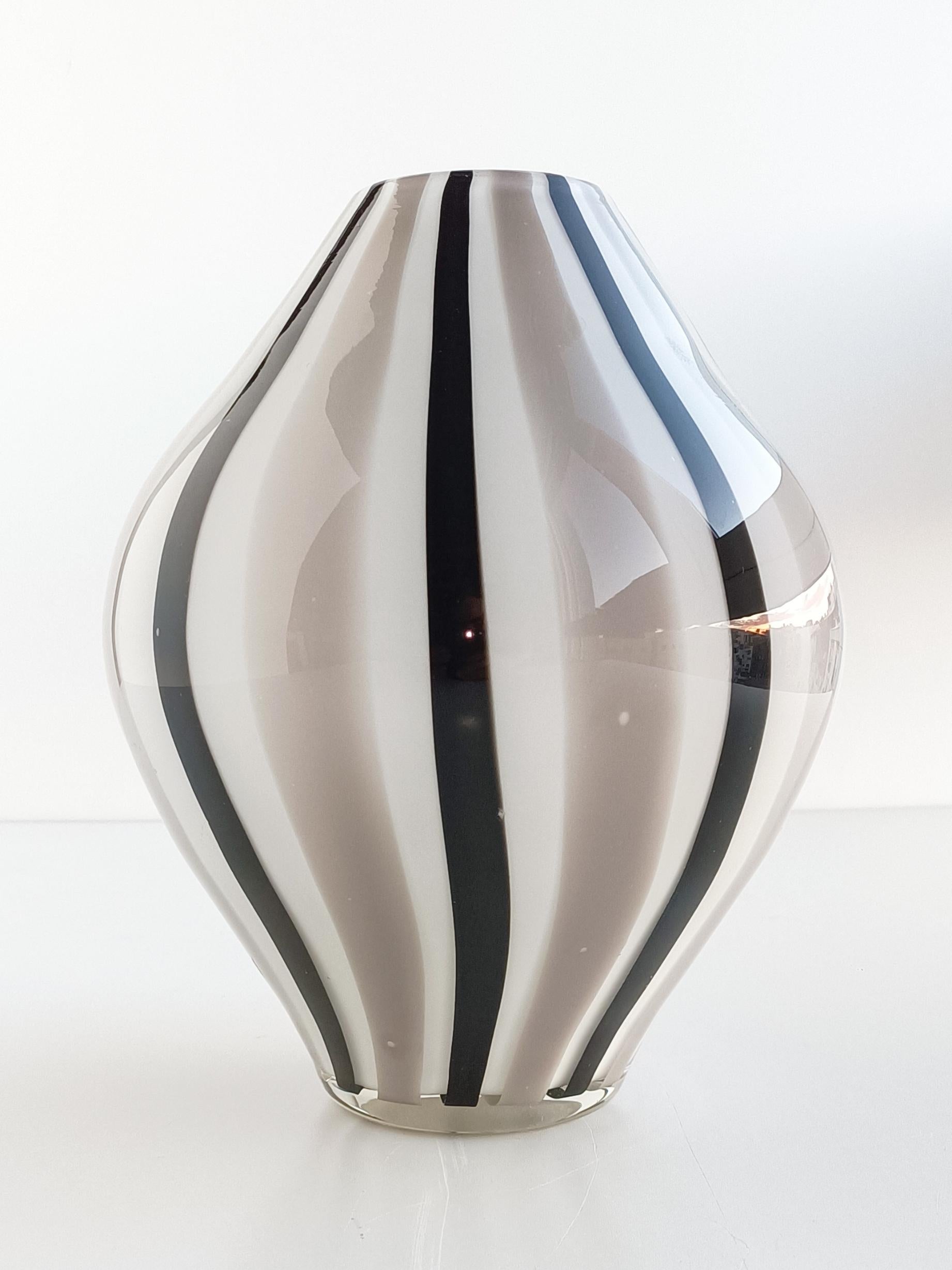 Explore the exquisite beauty of a vintage Murano glass vase. Featuring a very graphic unique striped decor in white, gray and black, this stunning piece will add elegance and charm to any space. 
Handcrafted in Venice, Italy, circa the 1960s.
