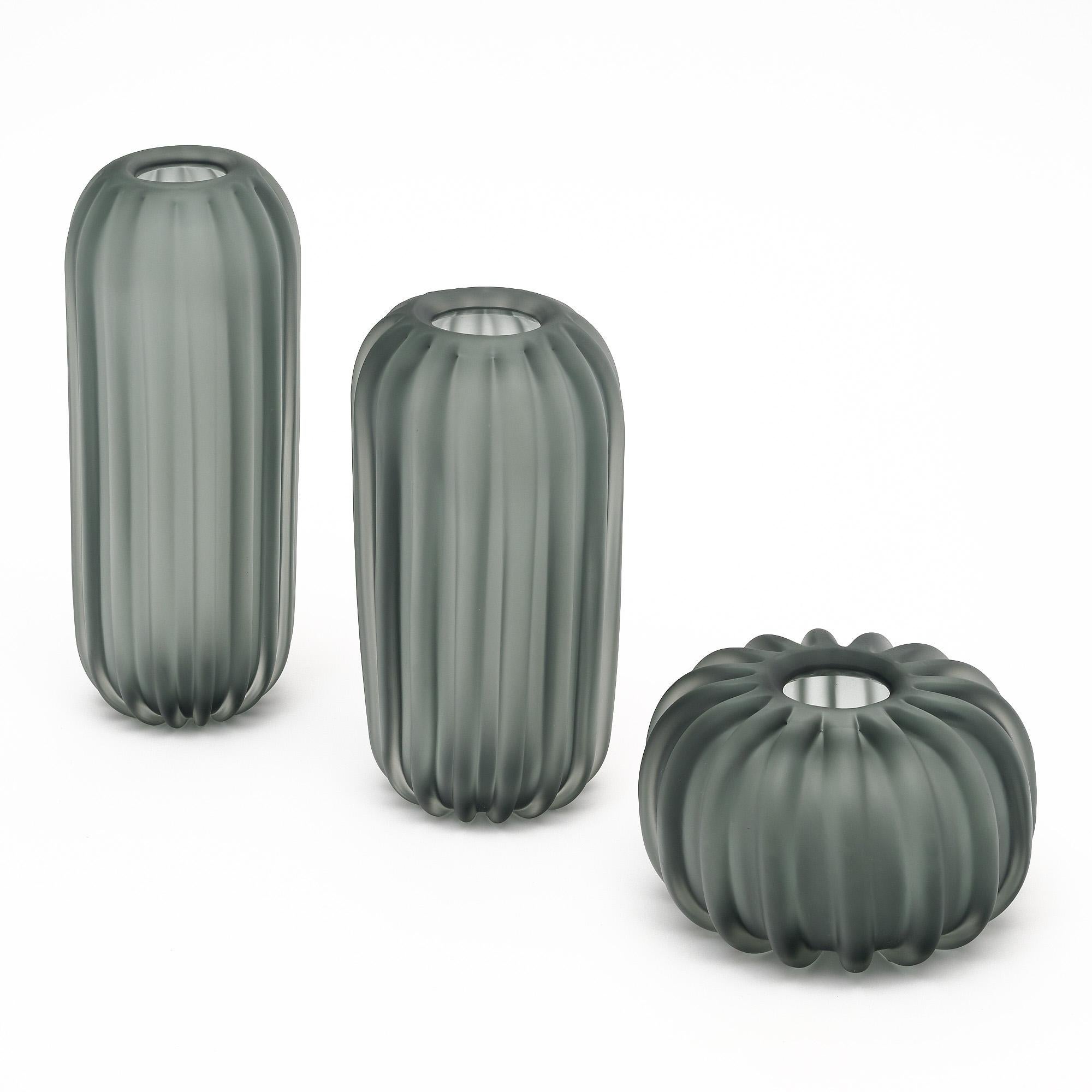 Set of three gray vases made of hand-blown Murano glass vases. Each vase differs in size, yet has the striking fluted detailing and frosted appearance that unites them.
Small vase - Diameter: 11.5” Height: 6.5”
Medium vase - Diameter: 8” Height:
