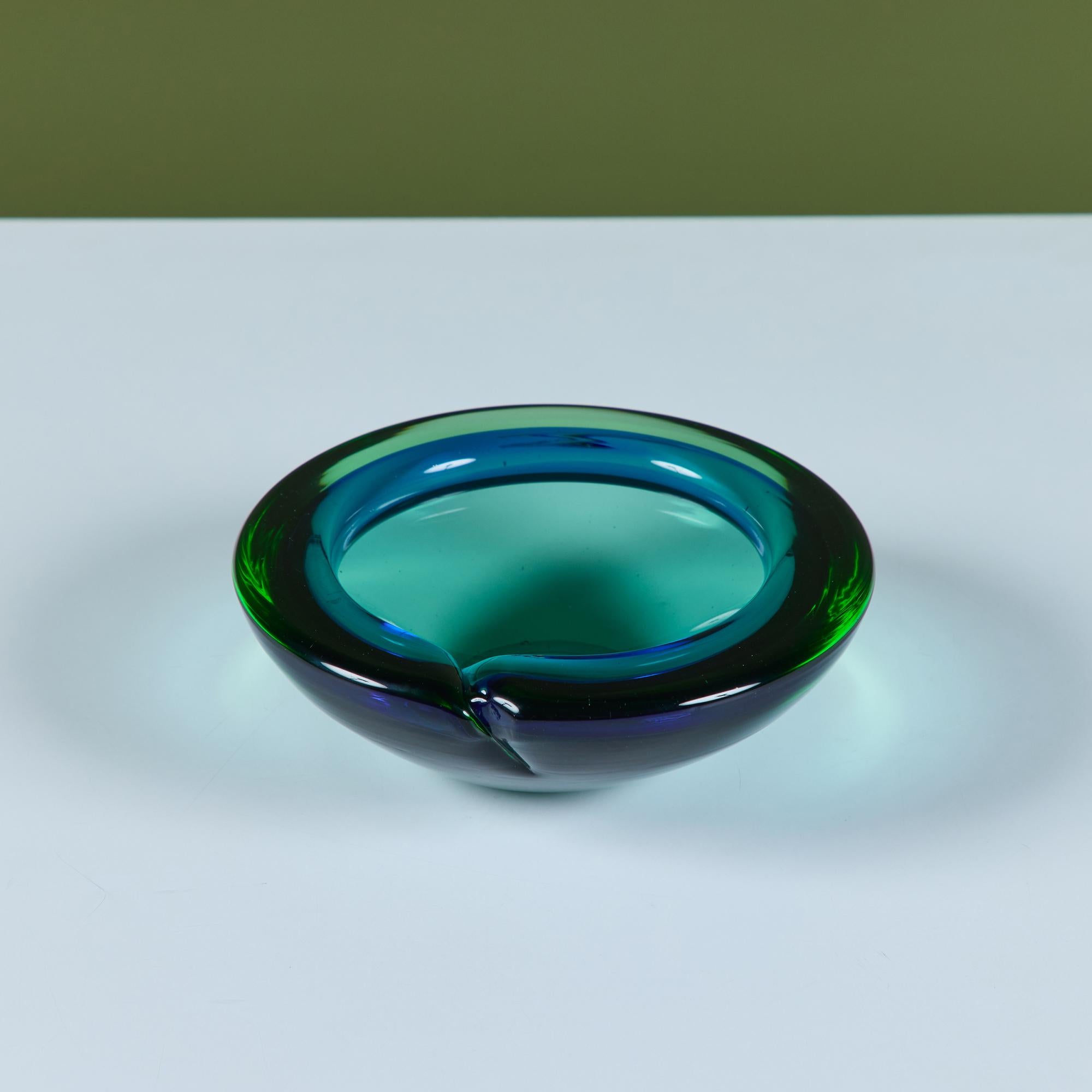 Italian Murano round glass ashtray or catchall, showcases a rich jewel tone in blue and green glass. This piece has a wide lip and deep well with a single notch for a cigarette or other smoking paraphernalia.

Dimensions
7.5