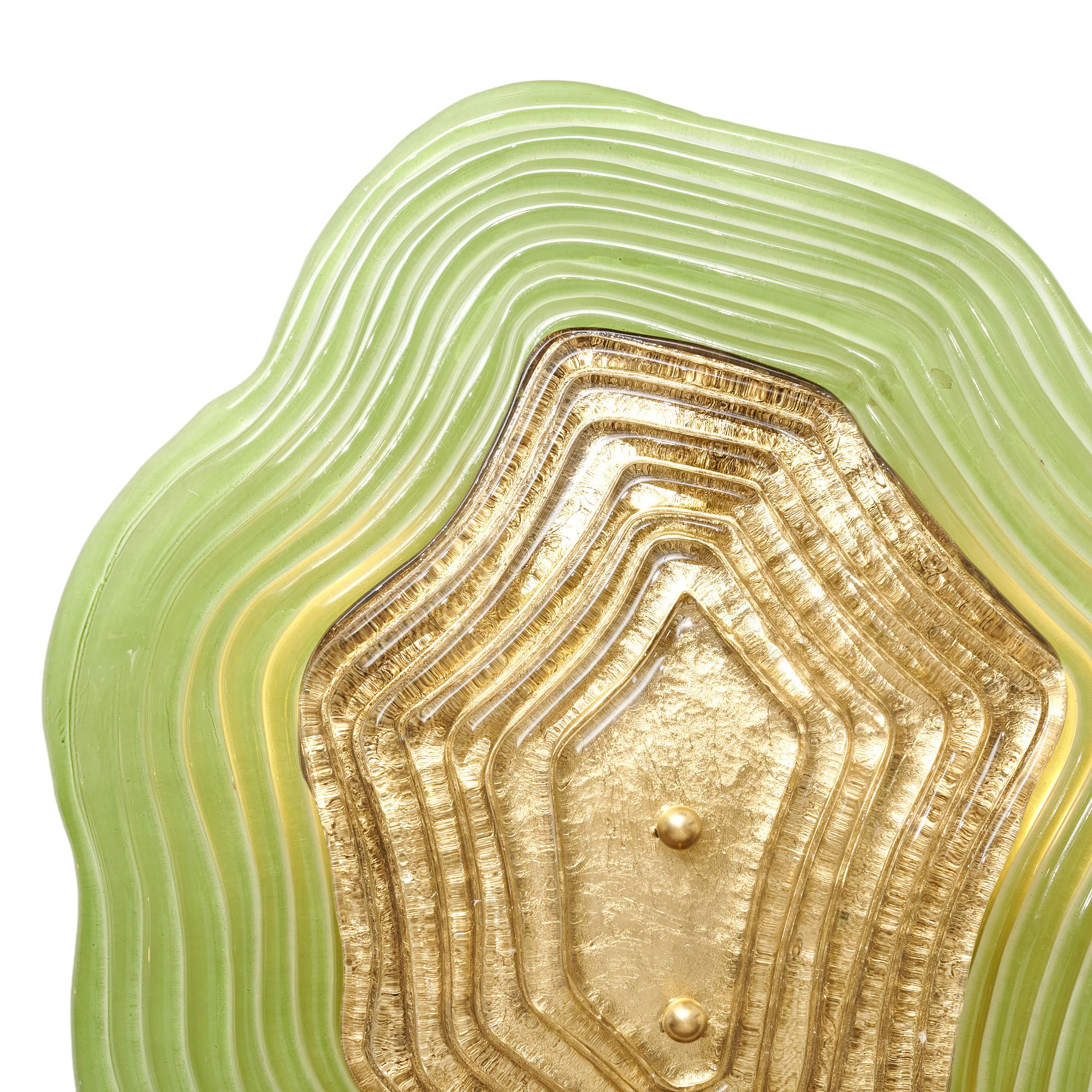 Pair of wall sconces from Murano island outside of Venice, Italy. This pair has two pieces of hand-blown glass layered and held in place by brass finials on a brass structure. The back piece of glass is a sage green hue. The top piece of glass is