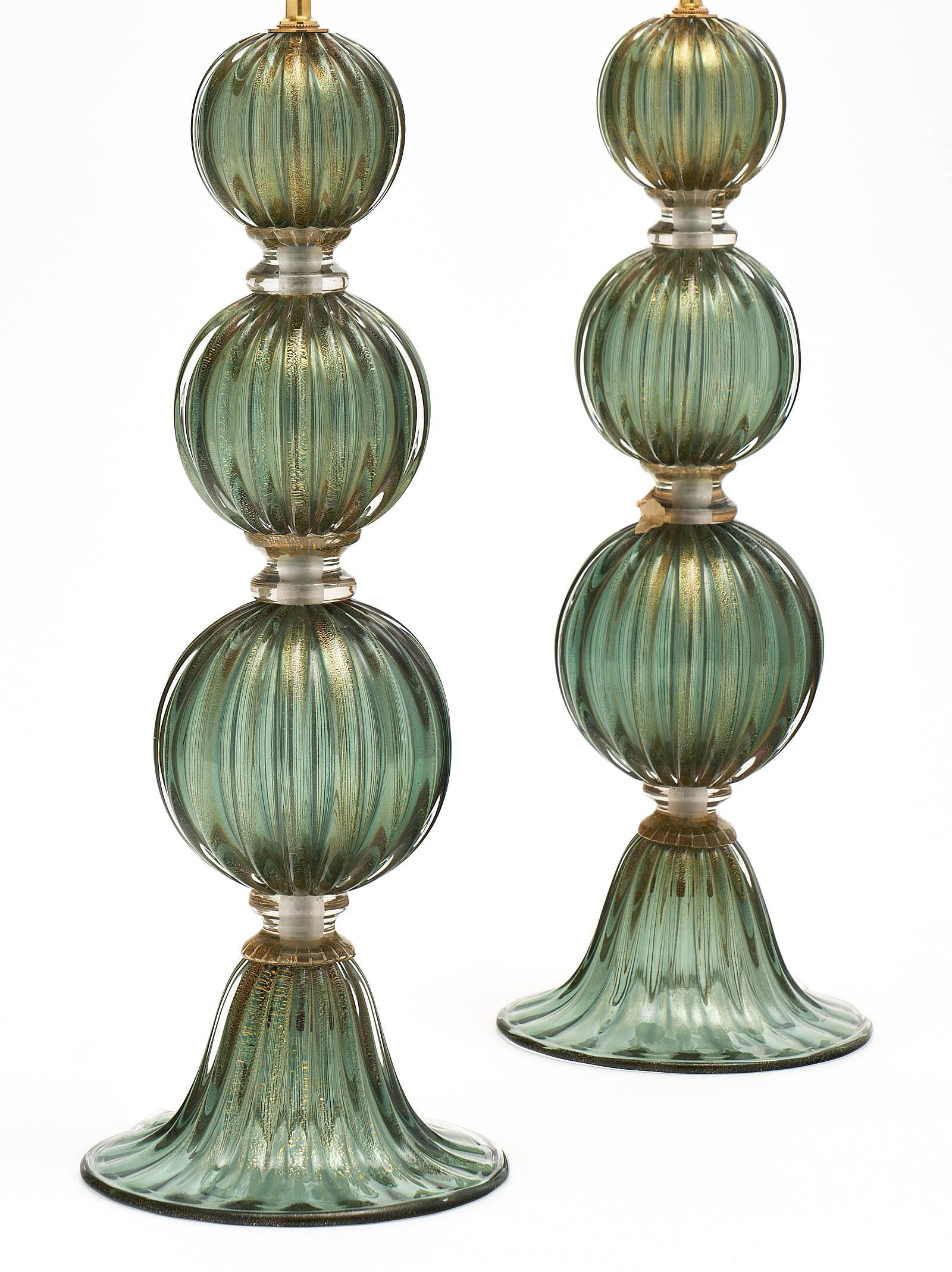 Green avventurina Murano glass lamps with four hand-blown segments of glass and a fluted base. The avventurina process involves fusing 23 carat gold flecks into the glass. This pair has been newly wired for US standards. The height of the glass