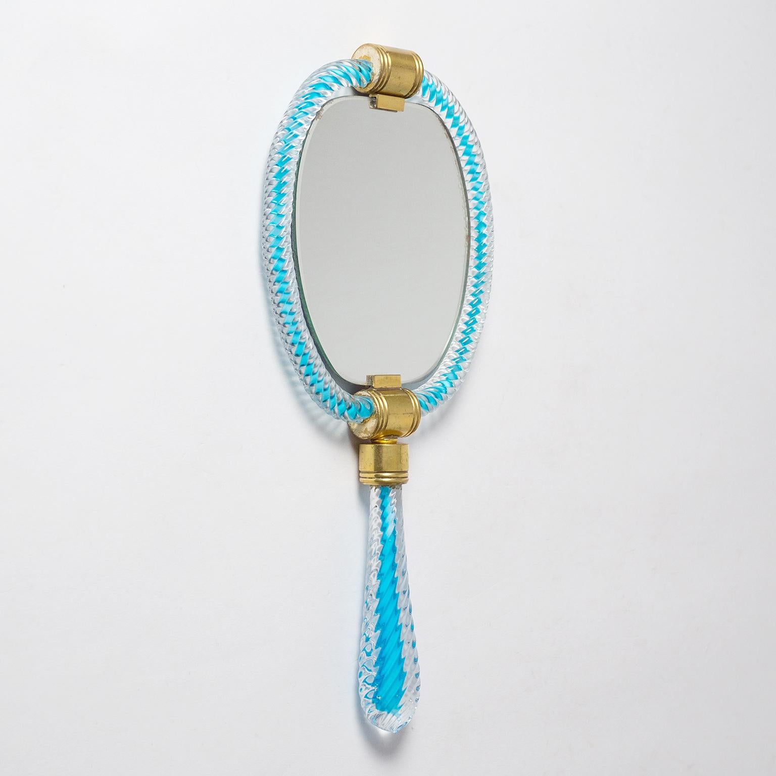 Charming Murano glass hand or vanity mirror from the 1940s. The glass is fashioned in 'treccia' (braided) technique with a rare light blue core which accentuates the optical effect of the braided glass. Fine original condition with a bit of patina