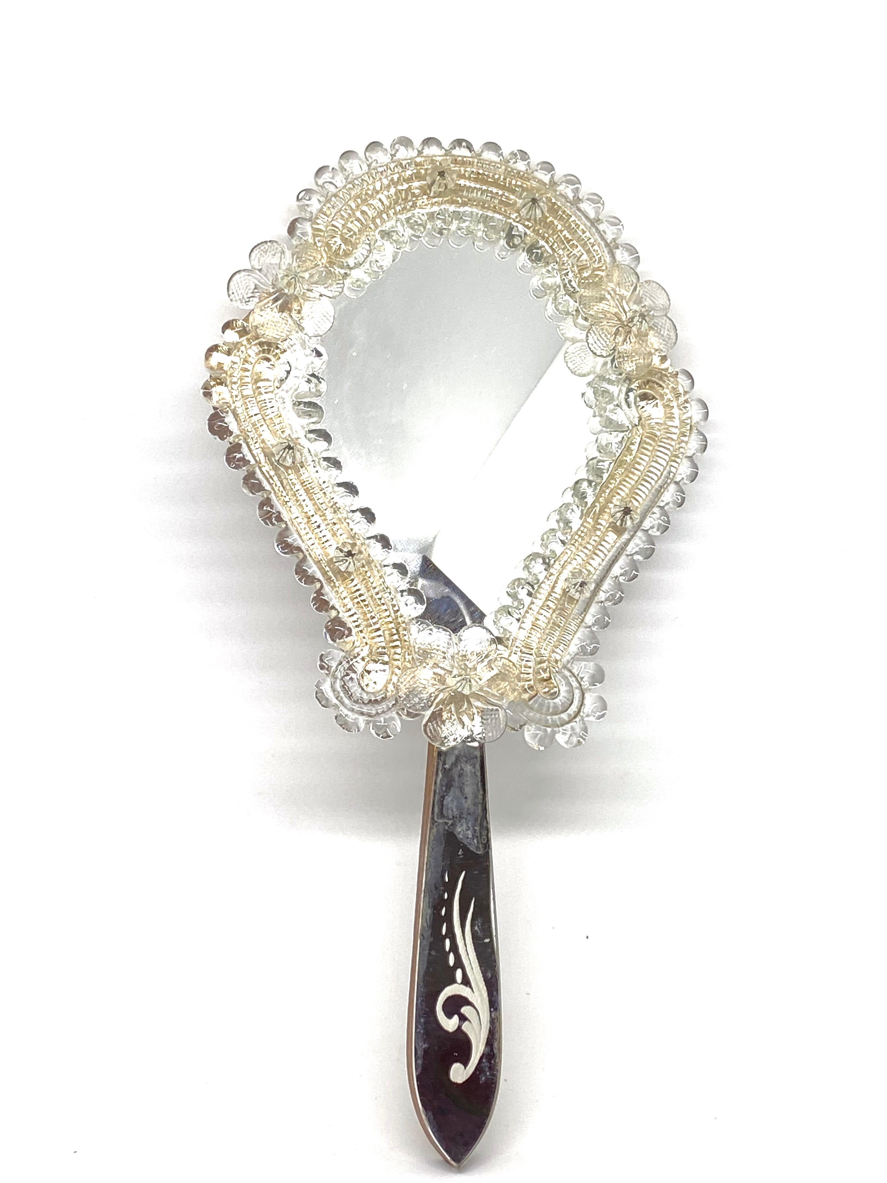 Uno splendido specchio per vanità in vetro di Murano circondato da fiori in vetro trasparente fatti a mano. Può essere utilizzato come specchio a mano o a parete. Con lievi segni di usura, come previsto dall'età e dall'uso. Una bella aggiunta a