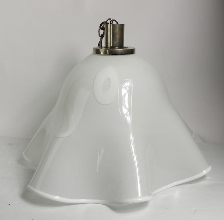 Apparecchio da appendere a forma di fazzoletto di Murano con attacchi cromati originali. Questo esemplare ha un fondo bianco, con punti decorativi bianchi a forma di ciambella. Il lampadario è in ottime condizioni, originale e funzionante, la parte