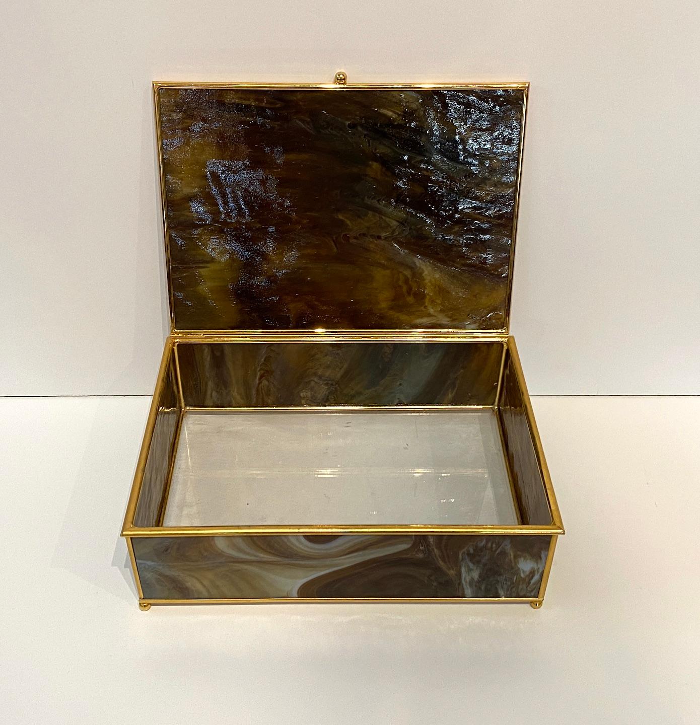 A stunning Murano glass paneled hinged box. Brass banding, knob and feet.  Clear glass bottom.