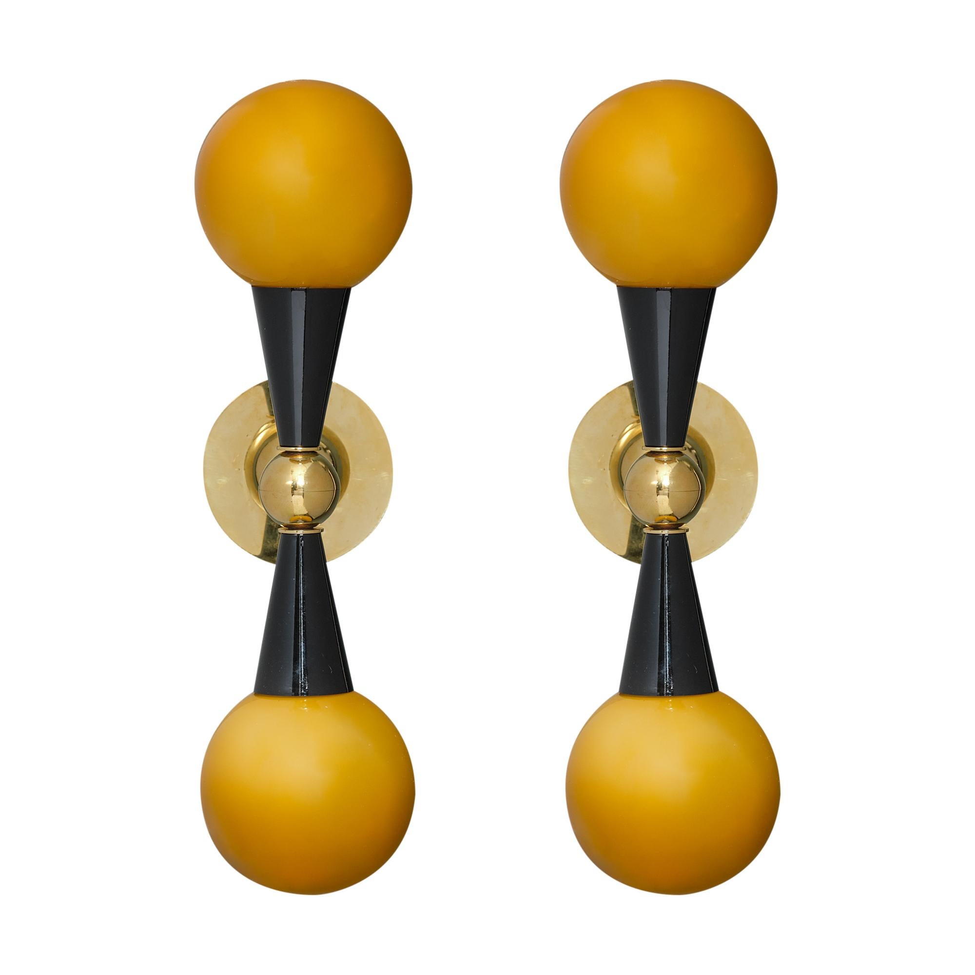 Italian Mid-Century Modern style wall sconces in the manner of Stilnovo. Murano glass globes and black laquered cones extend from a brass structure to create each of these stunning lights. The cones hold a hand-blown “Incamiciato” glass sphere. Each