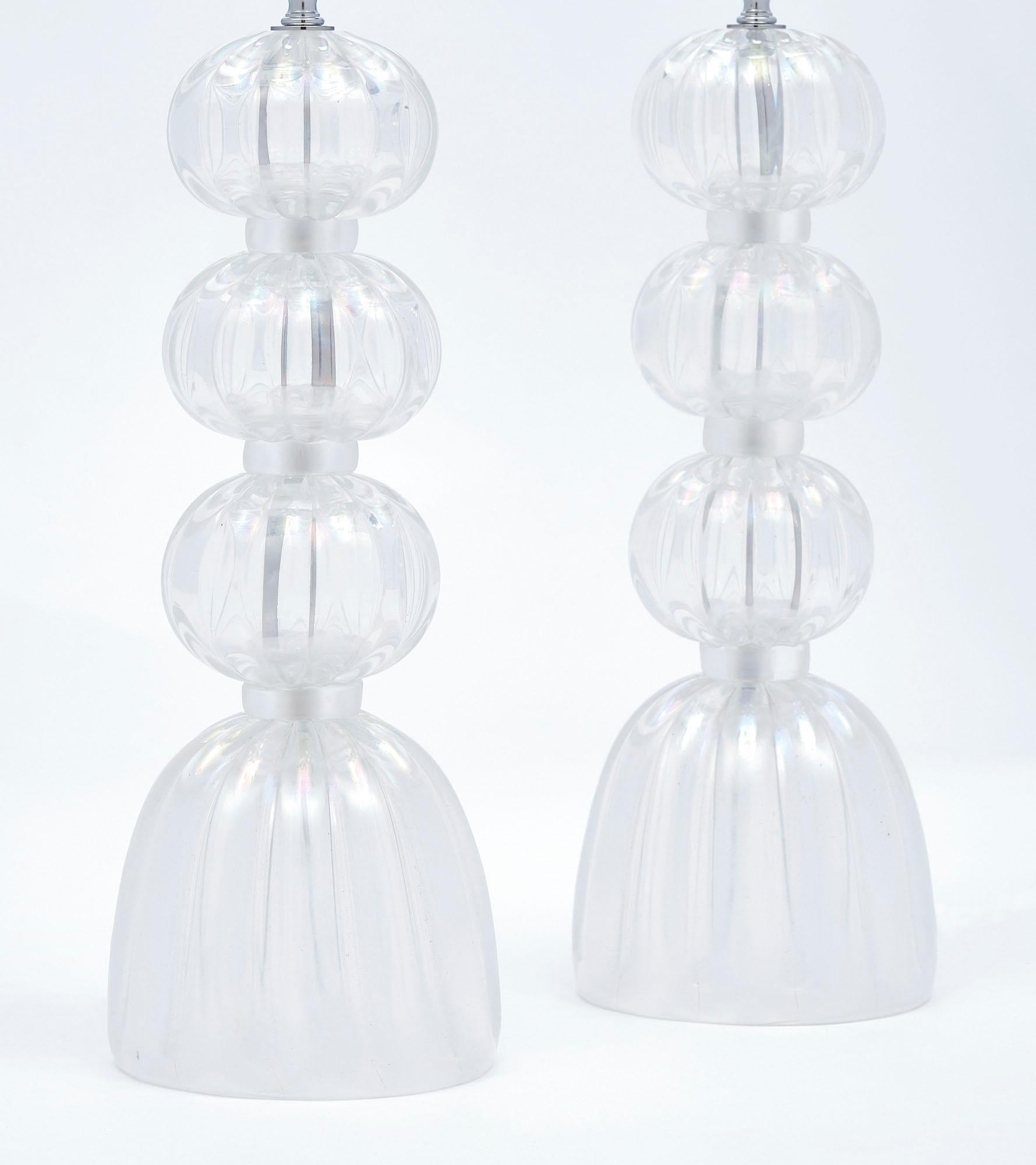 Pair of lamps, Italian, from the island of Murano made of clear glass spheres and base with an iridescent tone. The light reflected from the surface of the glass reflects off as colors of the rainbow. It is obtained by exposing the work in progress