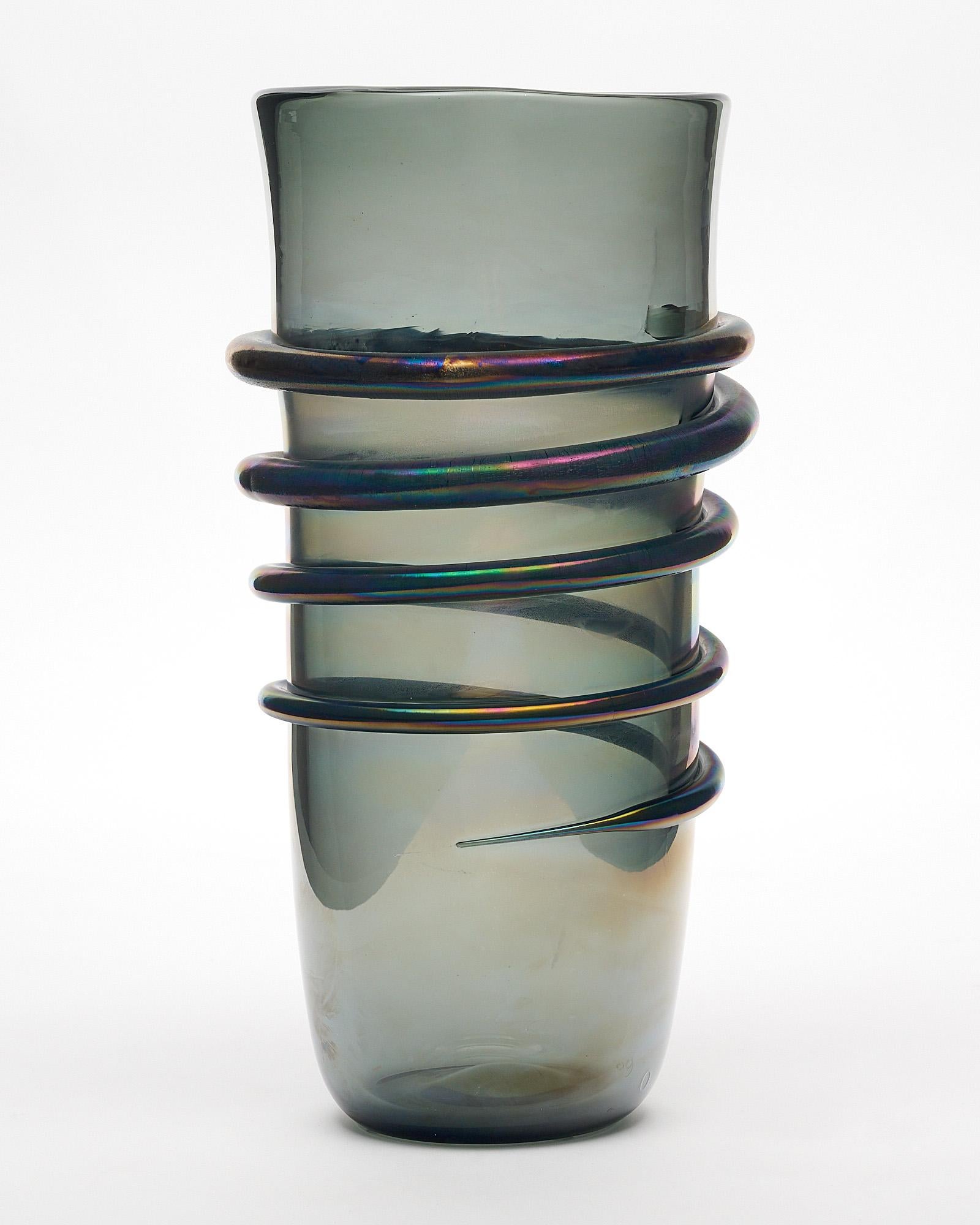 Murano glass vase made of hand-blown glass on the island off of Venice. This piece features dark smoked glass with an iridescent finish and hand-crafted “linee” or line wrapping around to create a spiral effect. We have two available; though they