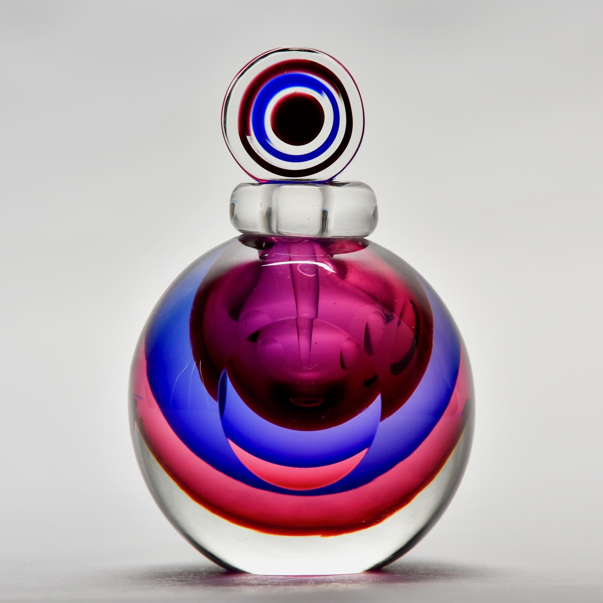 Der runde Parfümflakon aus Murano-Glas zeichnet sich durch seine schwere, klare Klasse aus, die durch Schichten aus fuchsia-, violett- und beerenfarbenen Juwelen im Sommerso-Stil unterstrichen wird. Oben ist ein Dufttupfer angebracht. Nicht