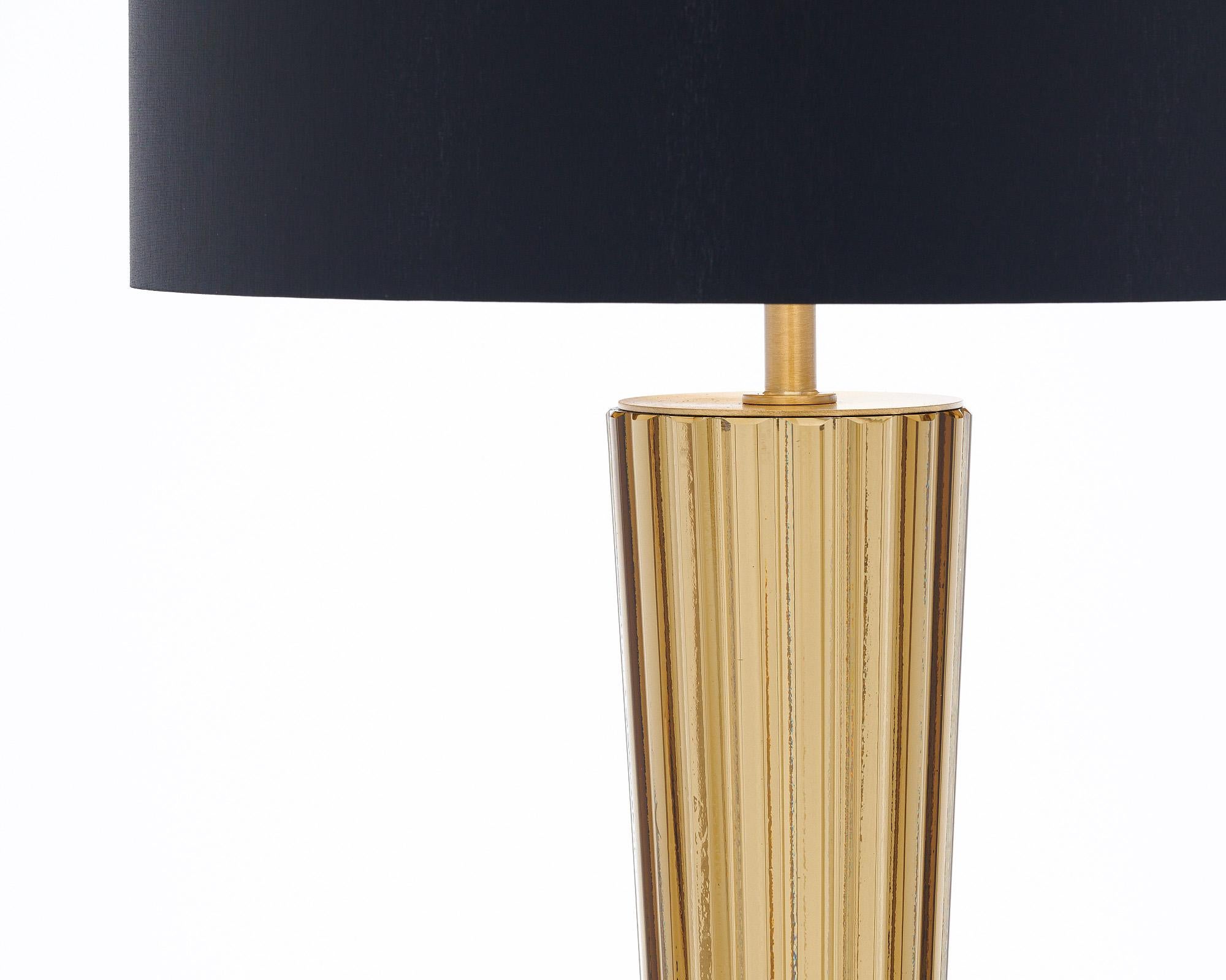 Coppia di lampade provenienti dall'isola di Murano, Italia. Ogni lampada è caratterizzata da un componente in vetro soffiato a mano e rigato in un caldo color oro fumé. Sono sostenuti da una struttura in ottone con una base quadrata in vetro nero.