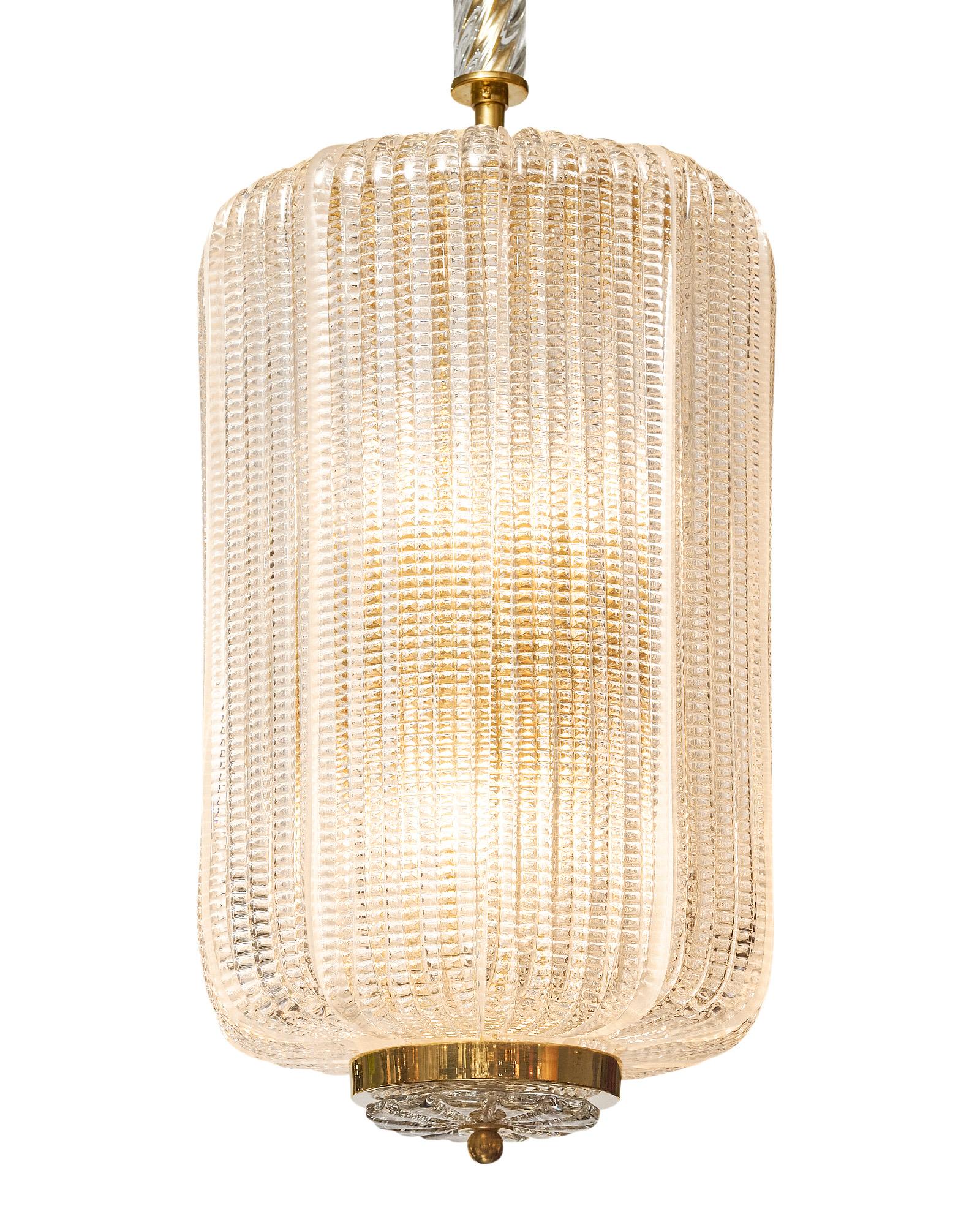 Lampadario a lanterna in vetro di Murano soffiato a mano. Il corpo della lanterna presenta pannelli di vetro modellato attorno a una struttura in ottone. Anche l'asta è ricoperta di vetro soffiato a mano. Questo pezzo è stato cablato di recente per