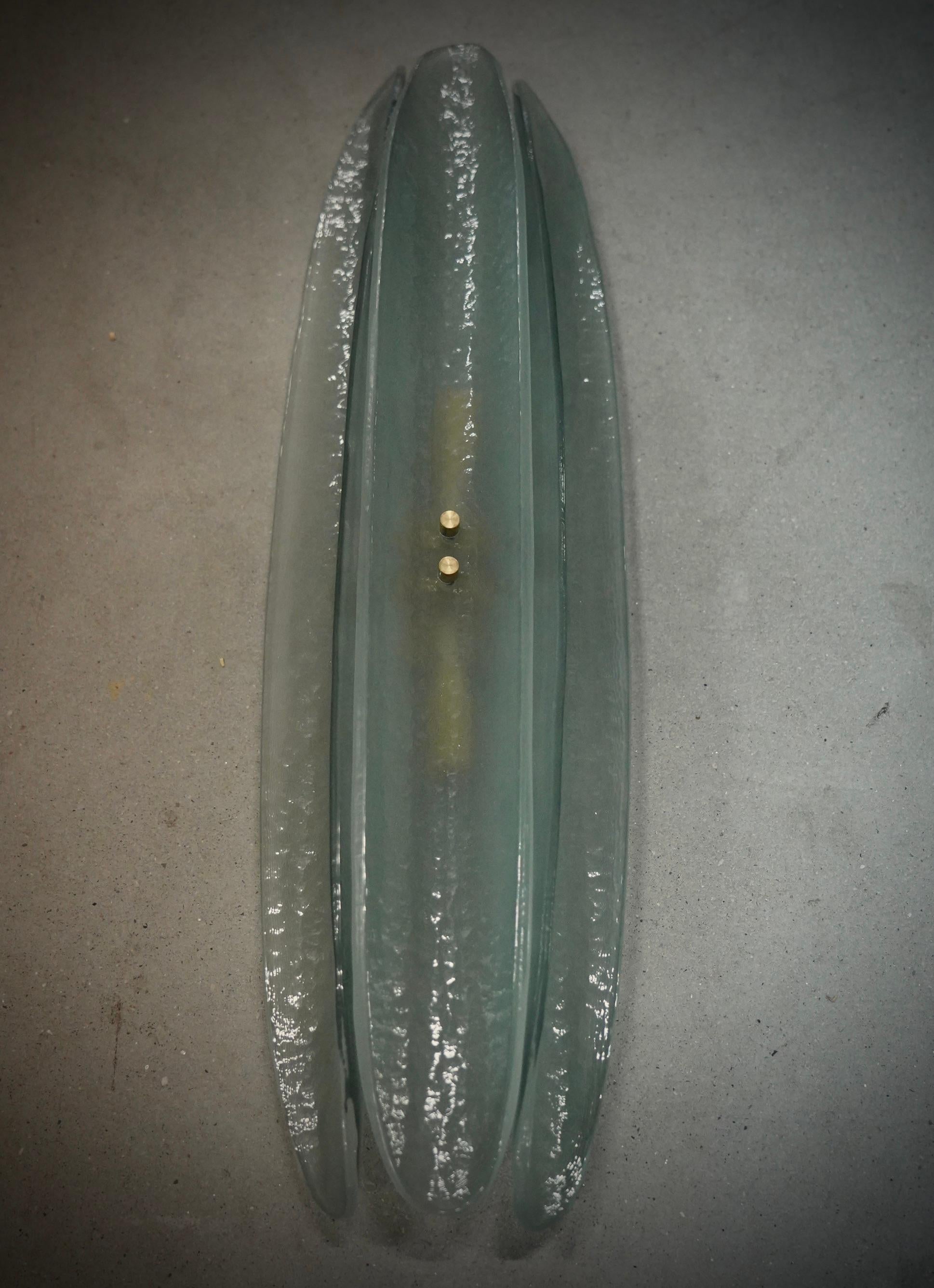 Very original Murano glass wall lamp with a very elongated design of the glass half shell and a unique light green color.

The applique is made up of a gold colored metal structure to which three very particular Murano glass half-shells have been