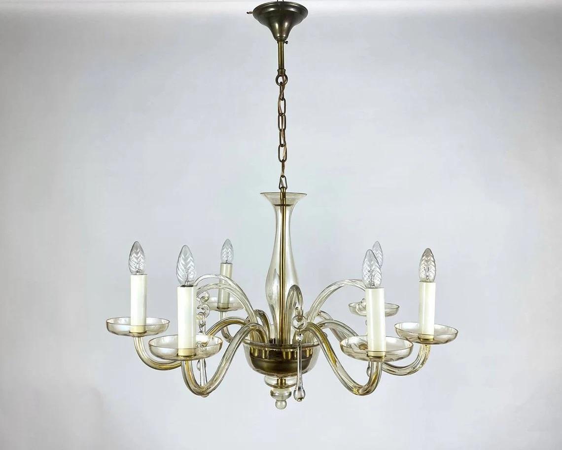 Lovely Murano glass and gilt metal vintage chandelier.

Circa 1970s Chandelier with six candle arms.

Italy.

The framework is in gilt metal, surrounded by 100% transparent Murano Glass that capture and reflect the light of the candle