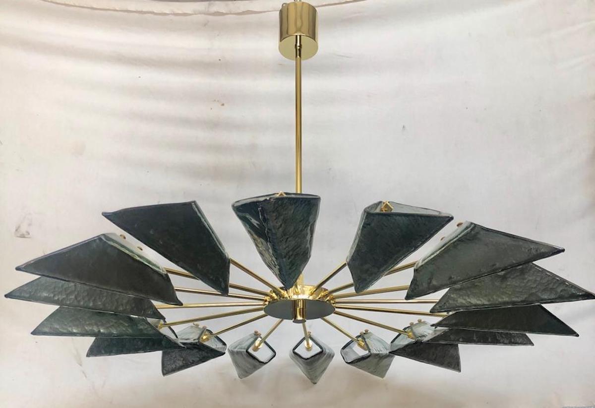 Simple and linear but there is all the style of Murano in this splendid chandelier with a beautiful green / blue color.

The chandelier has a structure made of polished brass tubes, to which particular Murano glass tiles have been inserted; note the