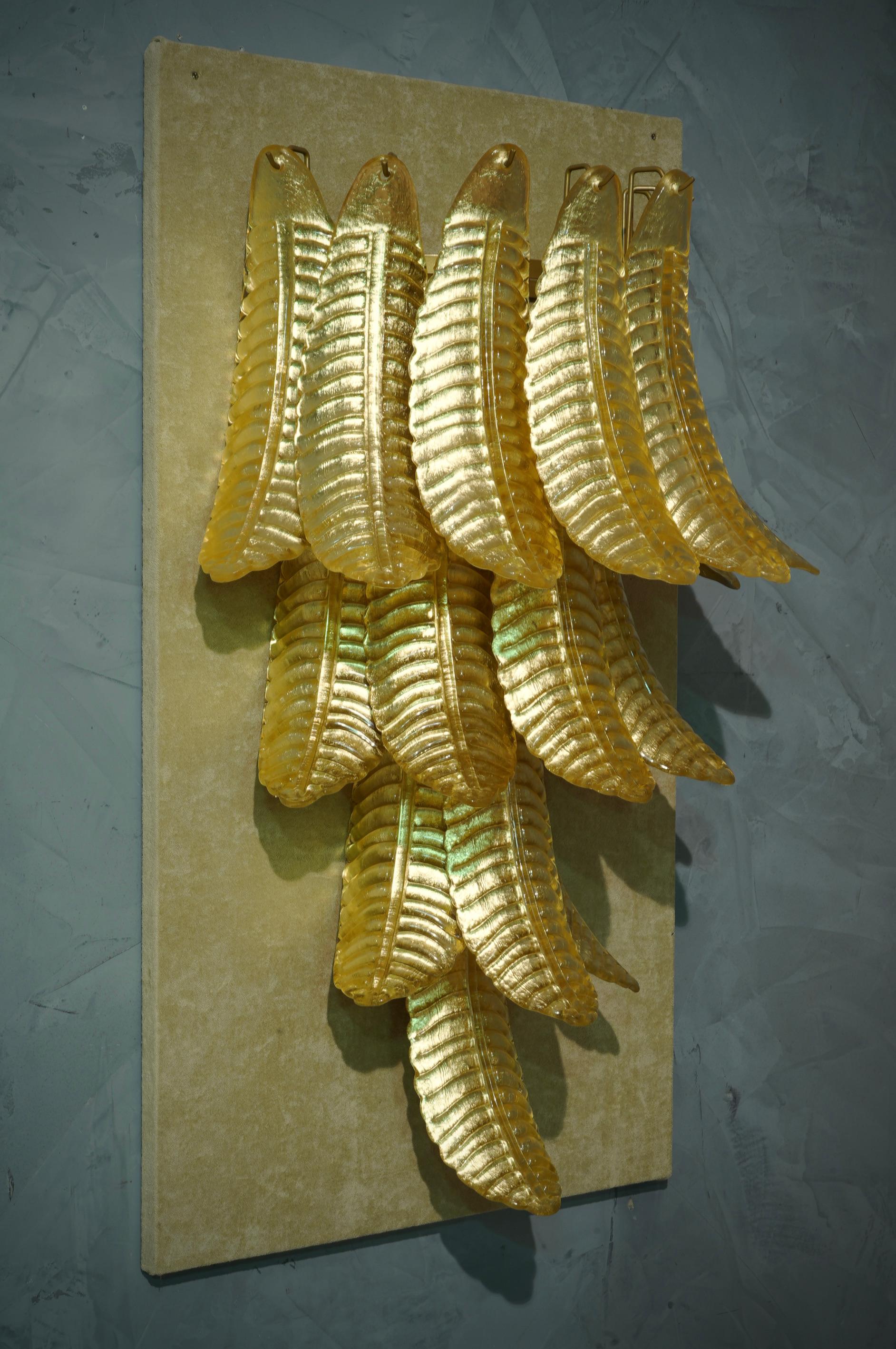 Sechzehn wunderschöne Blätter aus klassischem goldfarbenem Murano-Glas. Reiches Design für eine wirklich schöne Wandleuchte. Schlicht und elegant im Stil von Mazzega.

Die Applikation besteht aus einer Reihe von sechzehn goldenen