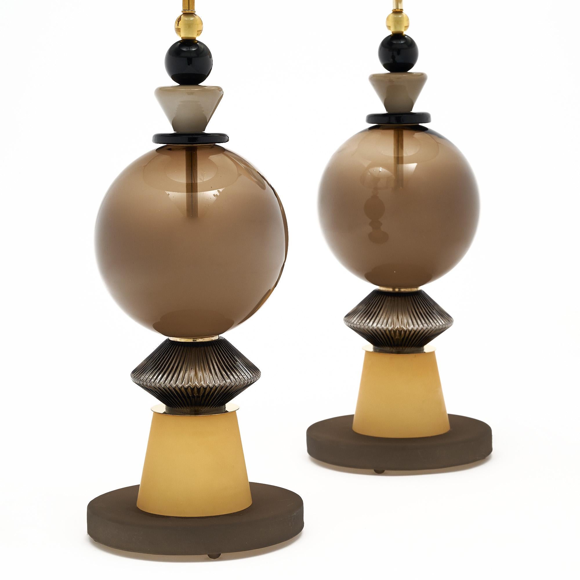 Pair of hand-blown Murano glass lamps featuring unique glass components supported on a brass structure. In the style of iconic Italian designer Ettore Sottsass. We love the taupe and black tones of the geometric formed glass. The gold shades are