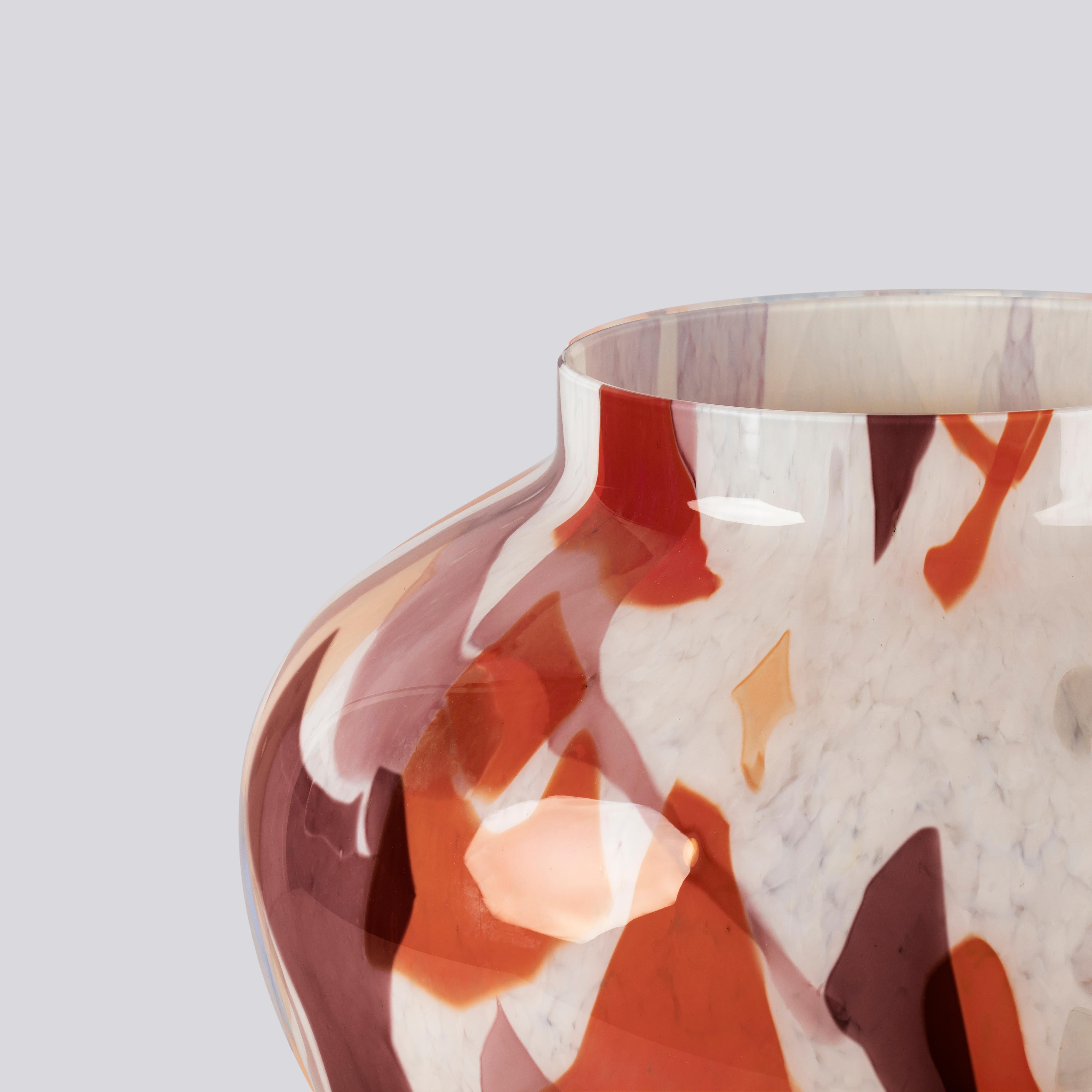 Handcrafted by skilled artisans from Murano, Italy, this vase captures the vibrant colors of autumn. Gray, red, and amethyst glass shards are meticulously arranged on an ivory base, showcasing exceptional craftsmanship and creativity. The swirls of