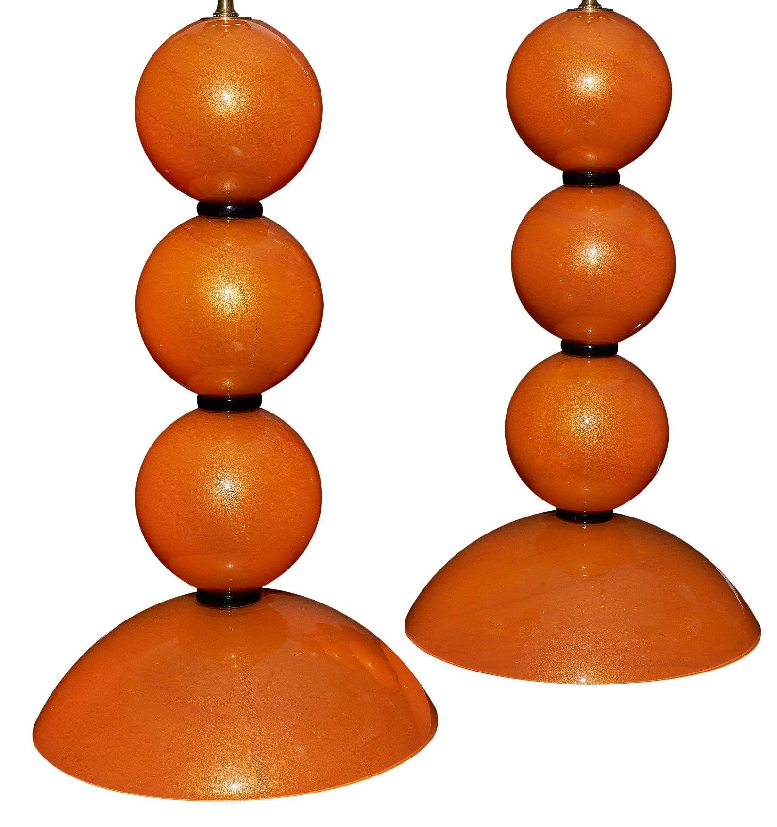 Stunning orange handblown glass lamps by A Dona in Murano. This pair as an exquisite, bright color and gold flecked throughout. They have been wired to fit US standards.

This pair is currently located at our dealer's warehouse in Italy. Please