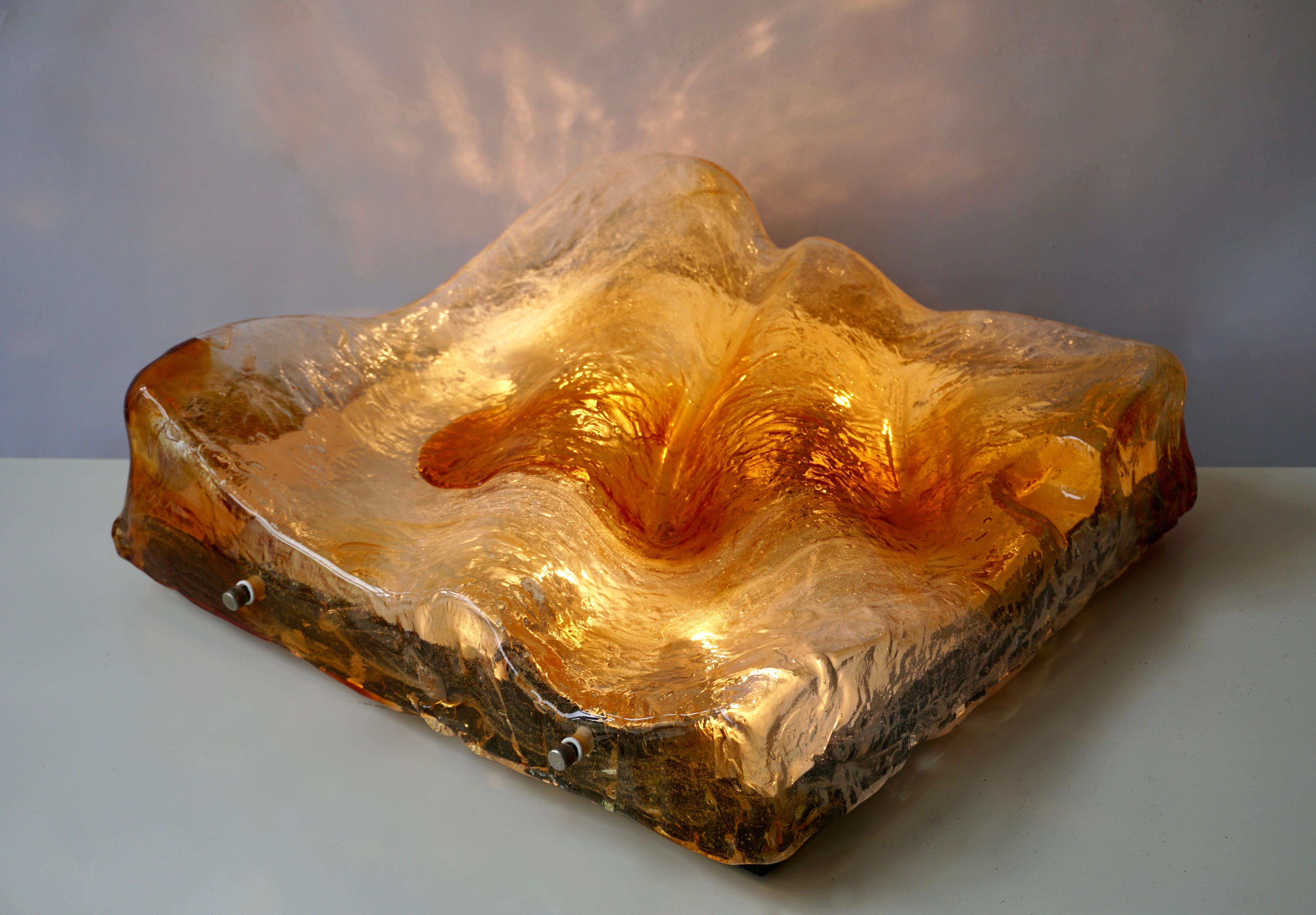 Grand plafonnier carré en verre de Murano de couleur ambre avec plaque arrière en métal par Mazzega. (Applique)

La lampe nécessite quatre ampoules à vis E14 (45 Watt max.).
Largeur 43 cm.
Hauteur 14 cm.
Poids 10 kg.