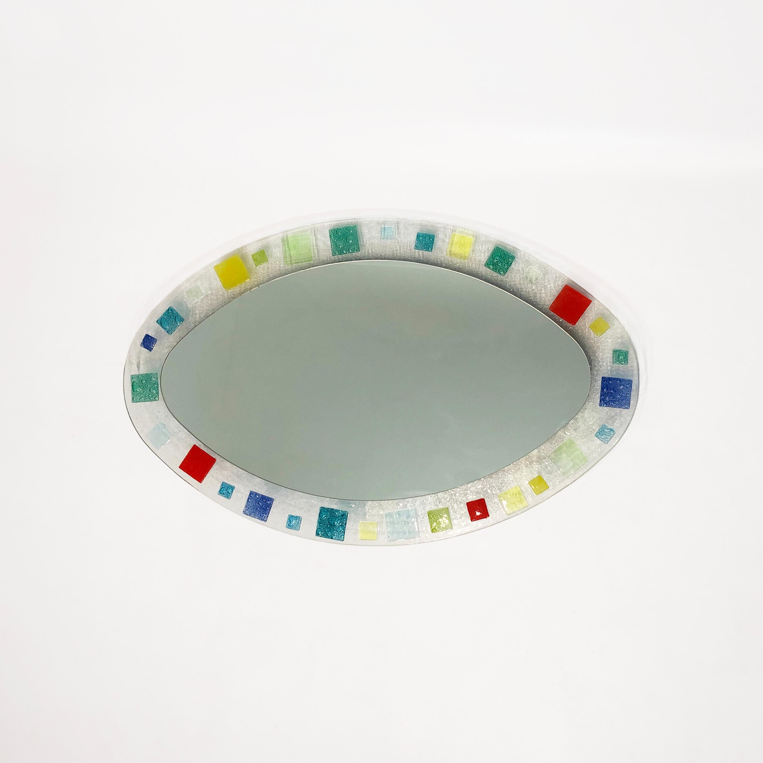 This small oval-shaped mirror, set in a hand-blown Murano glass frame and backed by veneered wood, would make a perfect edition in both maximalist or minimalist rooms.. The vibrant reds, greens, and blues of the Italian glass edges draw the eye to