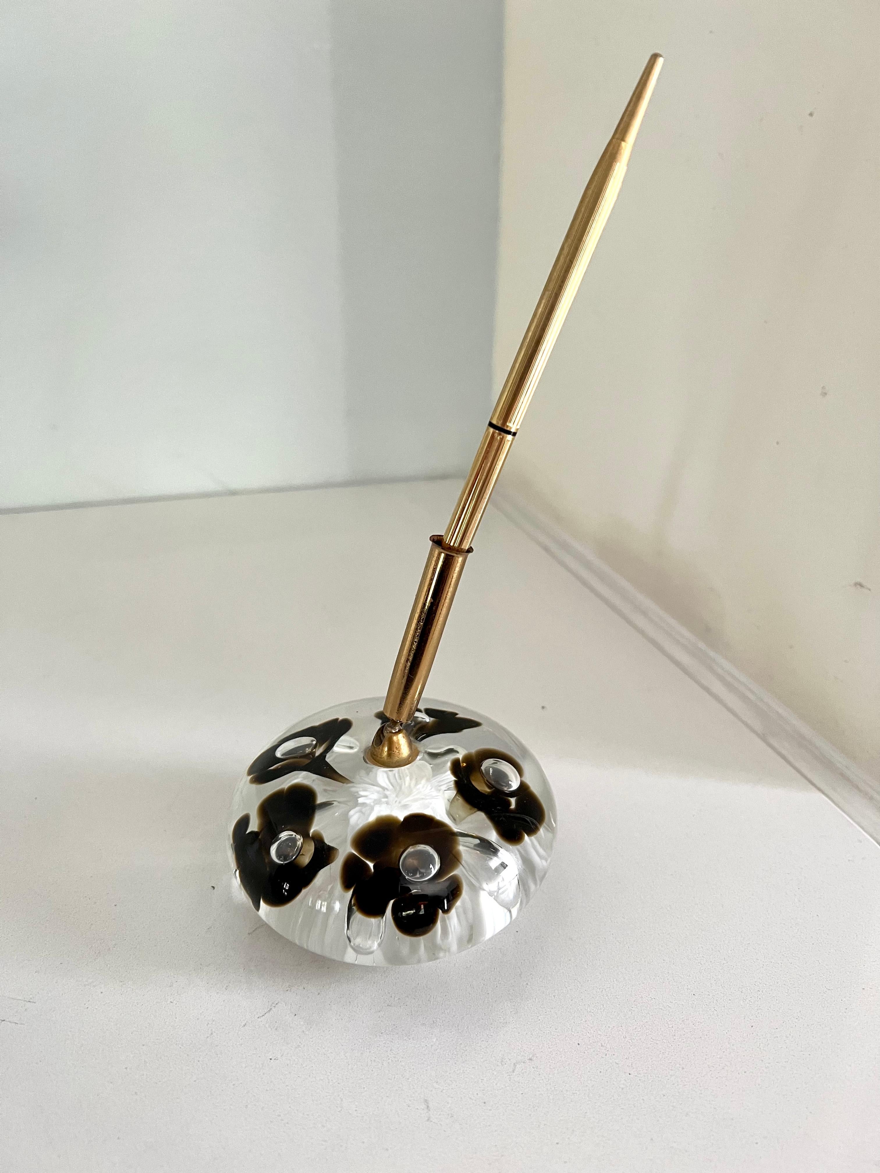 A beautiful glass paper weight with dark flowers encased - a holder for a lovely ribbed gold pen. The piece is great for any work station or well appointed desk.
