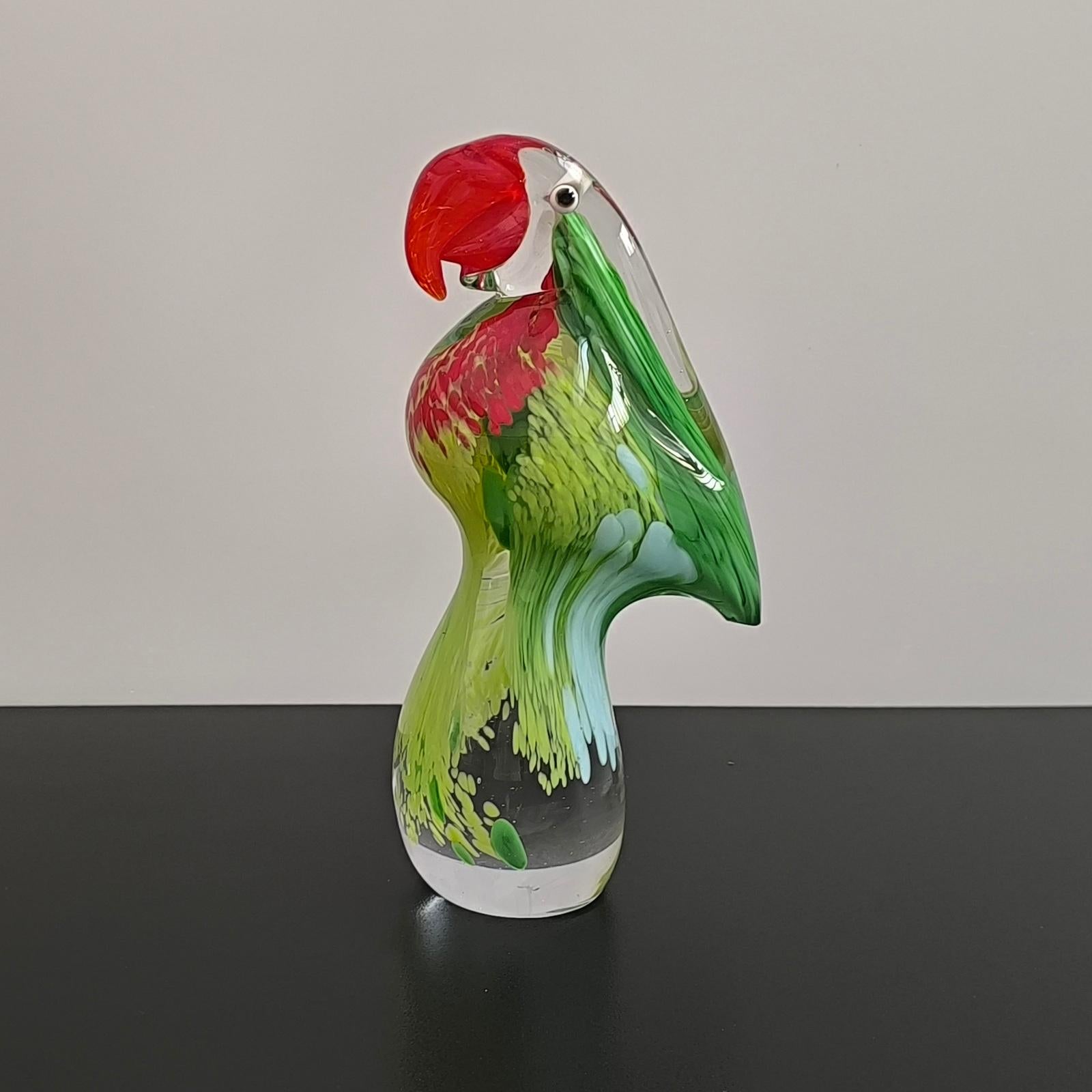Preciosa escultura de loro de cristal de Murano, hacia la década de 1970. La pieza está en muy buen estado vintage, sin astillas ni grietas. El pico de cristal rojo brillante aplicado sobre un cristal moteado verde claro y oscuro encerrado en