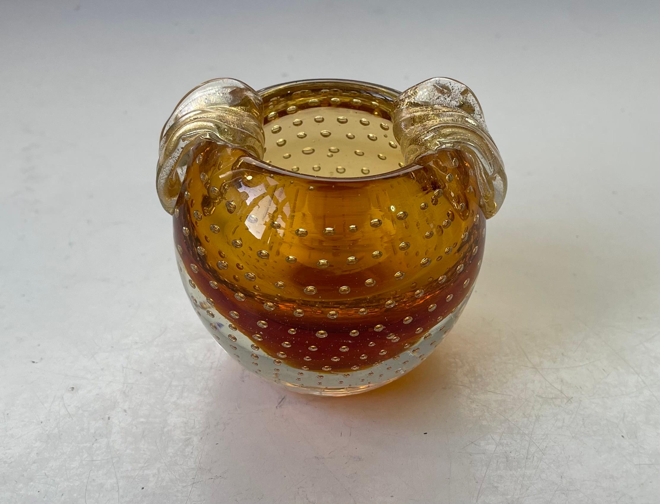 Un piatto o posacenere da pesca Venini con bolle d'aria controllate e polvere d'oro/fogliame. Realizzato a mano in Italia negli anni '50 o prima. Molto ben tenuto.   

Misure: H. H. 8,5, D. 9 cm al massimo della larghezza.