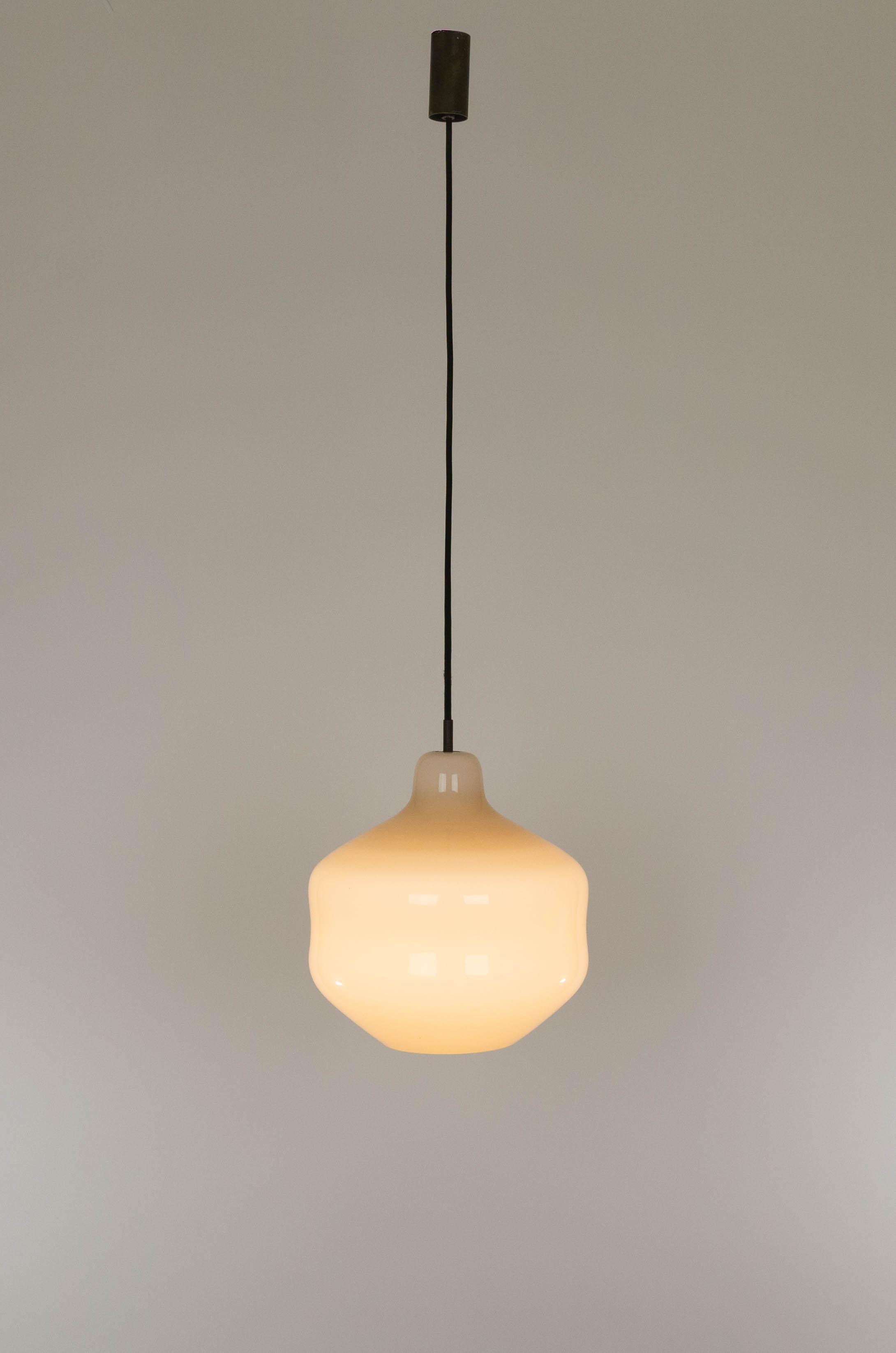Hand-blown glass pendant designed by Massimo Vignelli at the start of his impressive career in design and executed by Murano glass specialist Venini. 

The color of the lamp is light beige, turning to yellow or white when switched on, depending on